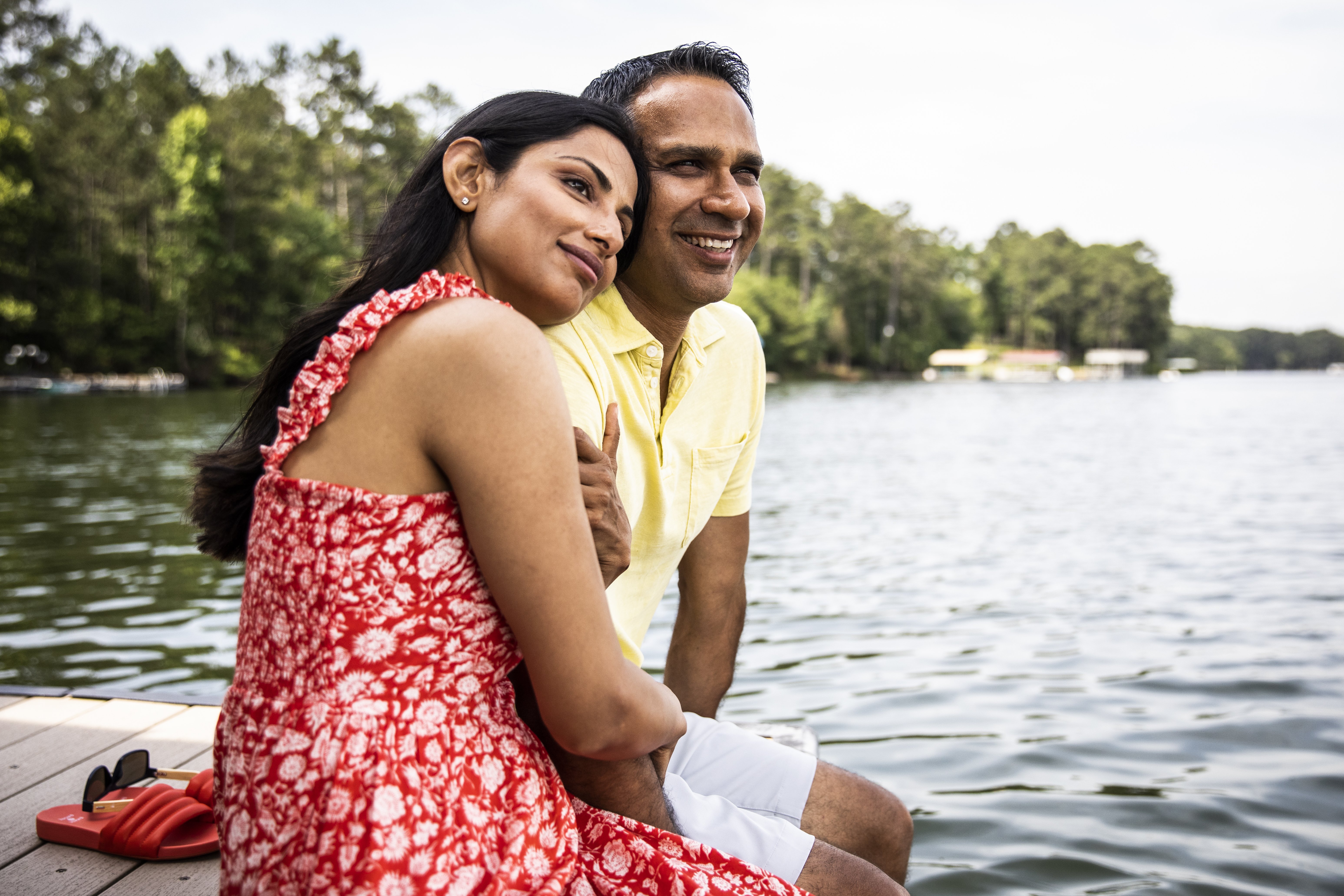 A couple sits on a dock by a lake