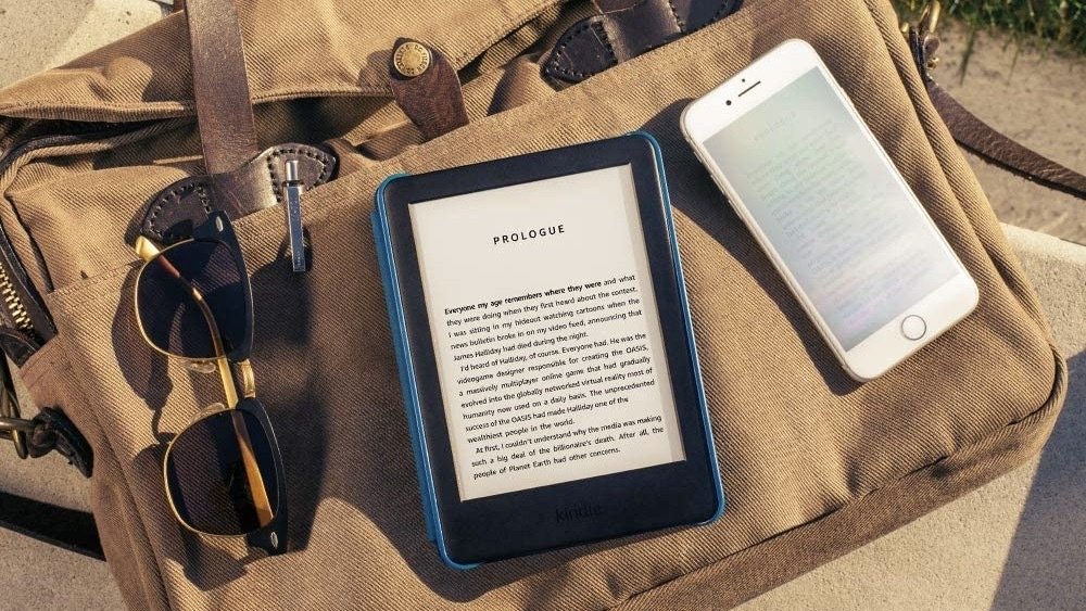 kindle on a bag alongside a phone and sunglasses