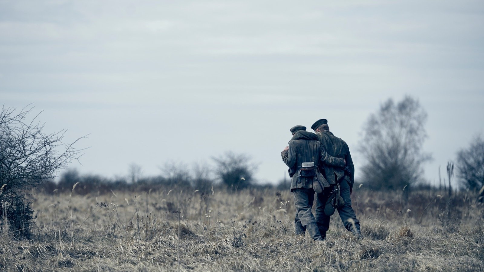 Two soldiers walk on a field arms wrapped around each other