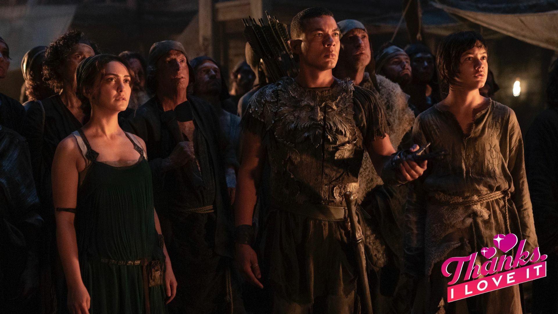 A human woman, an elven man in armor, and a young human boy stand at the head of a crowd of people, looking concerned.