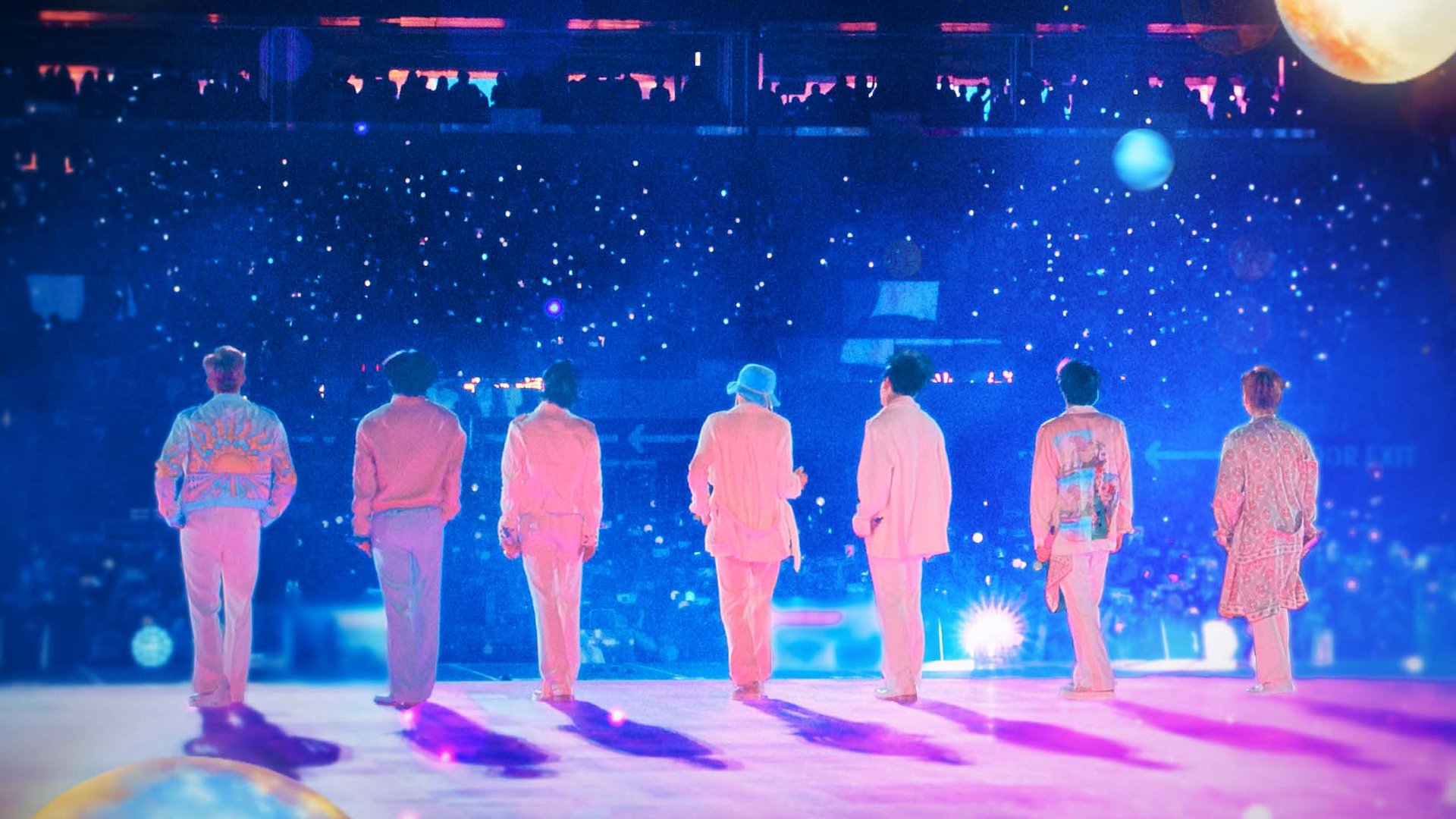 The seven K-pop band members of BTS stand in front of a massive crowd.