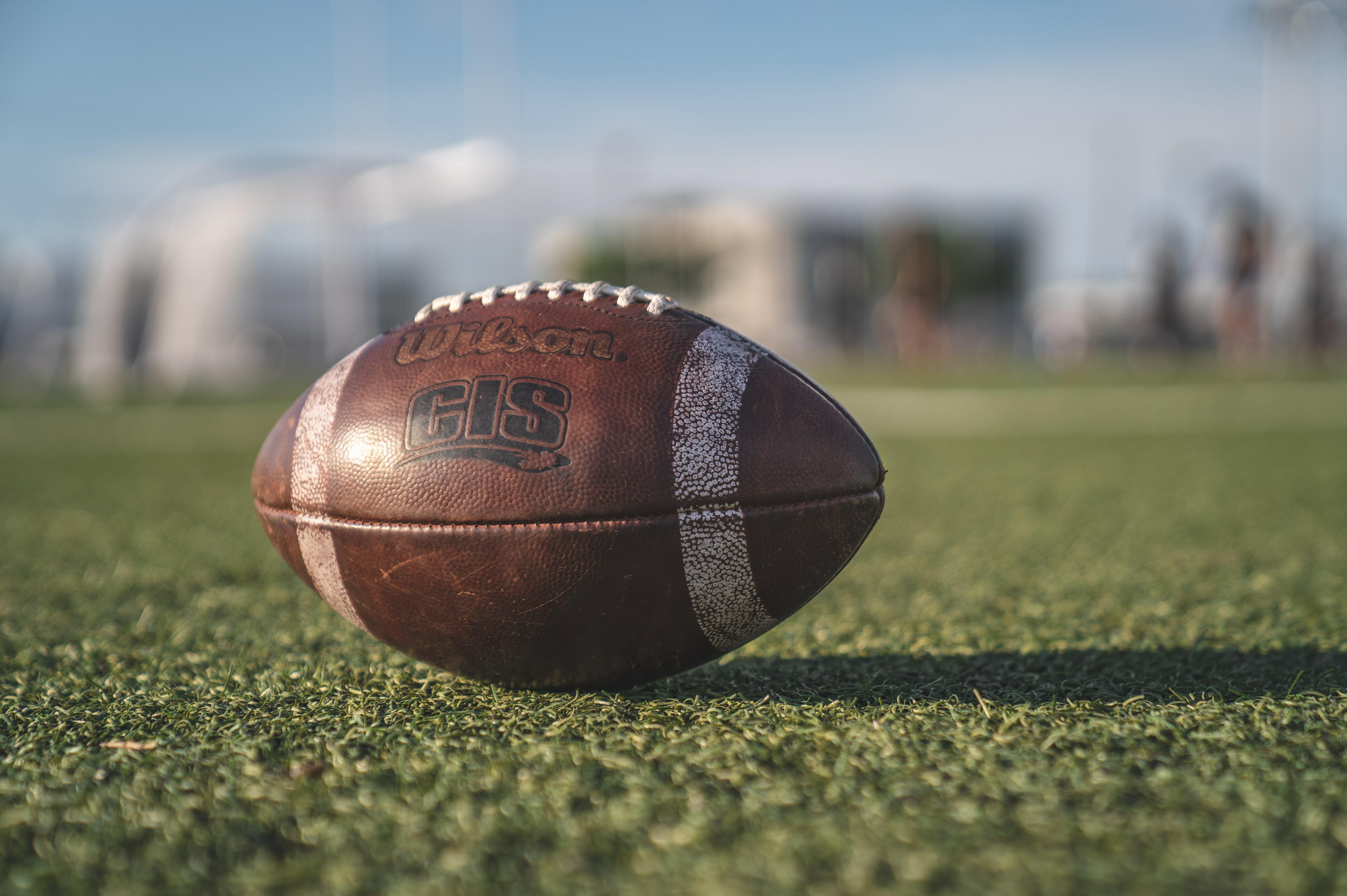 a lone football sits on some green turf