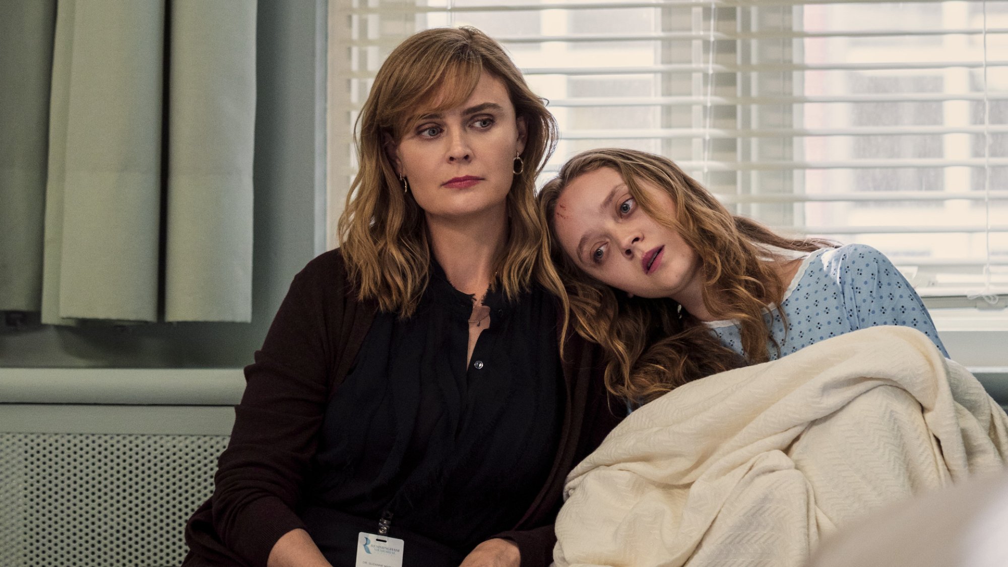 Two women sit in a hospital ward.