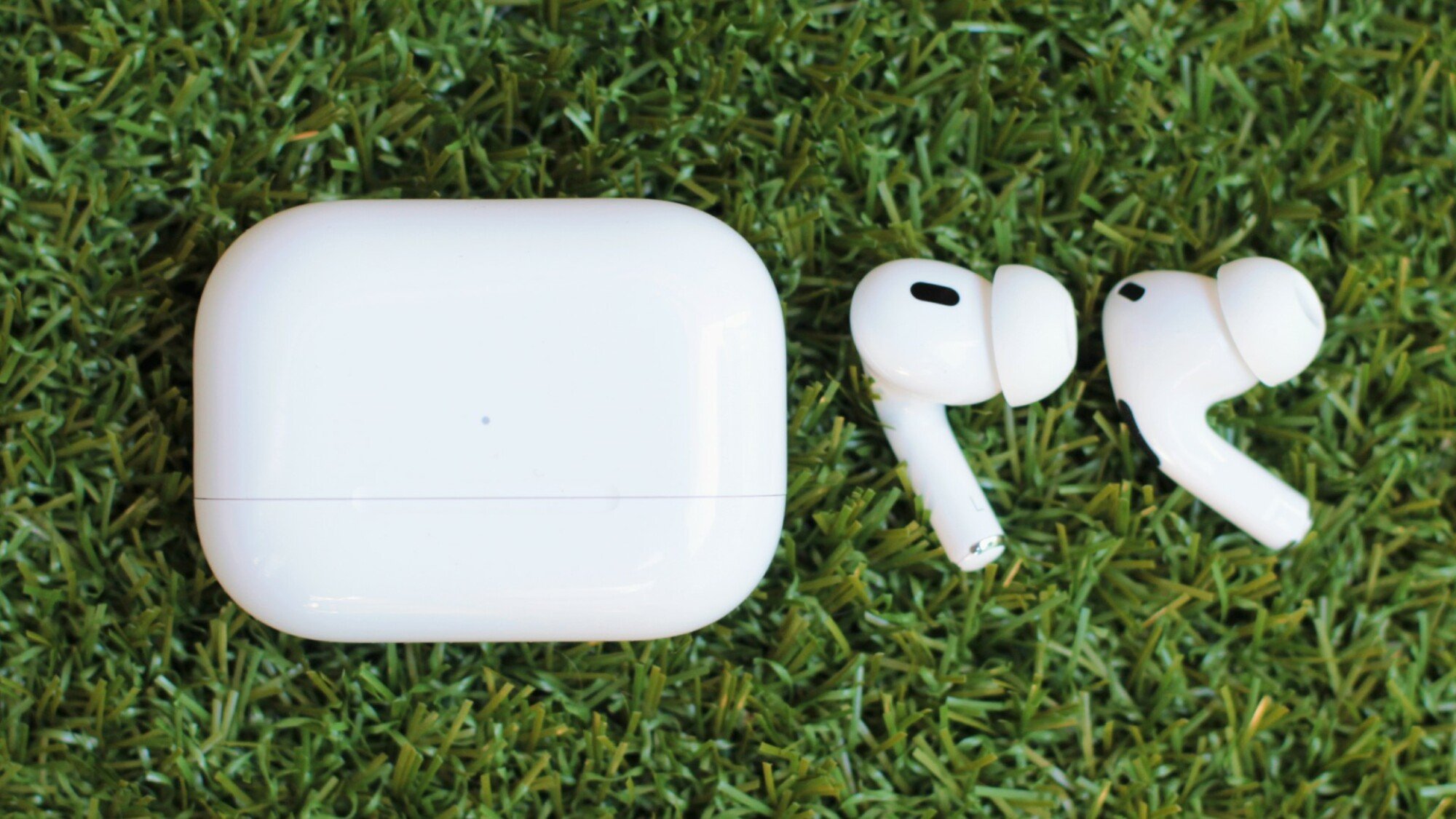 Apple AirPods Pro 2 and charging case lying in a field of green grass
