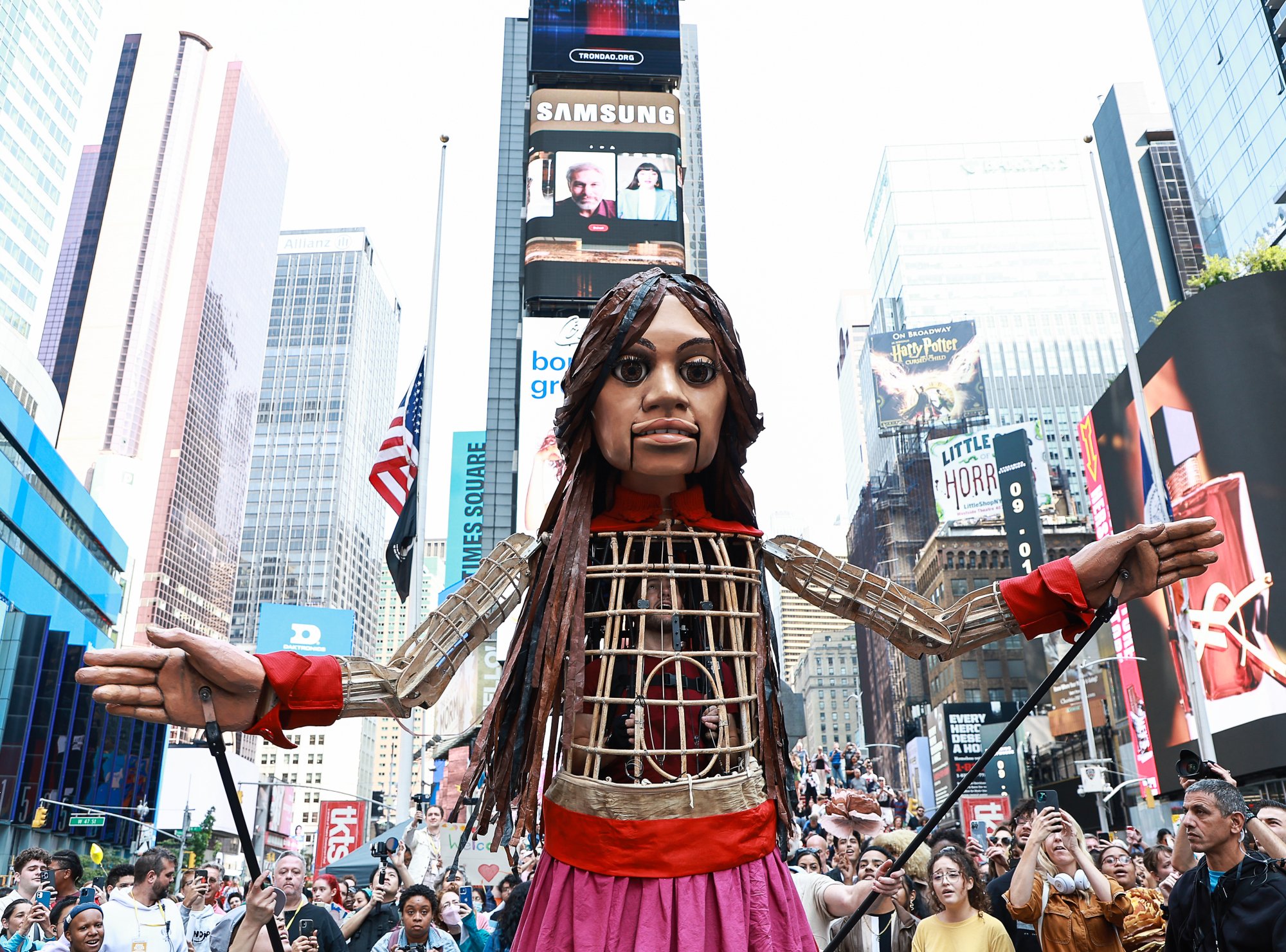 Amal stands with her arms outstretched in Times Square.