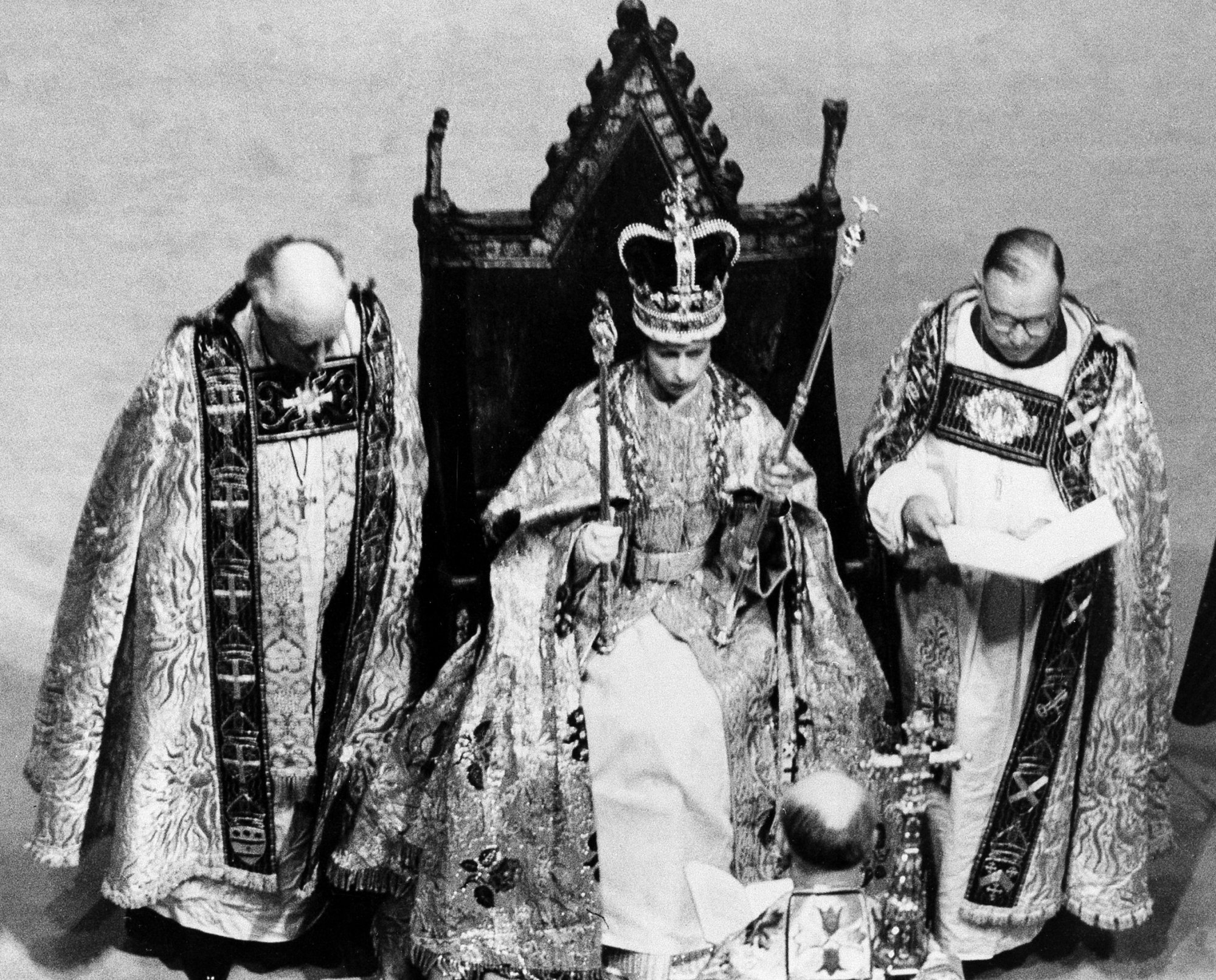 Queen Elizabeth II sits in King Edward's chair after receiving the crown, scepter and rod from the Archbishop of Canterbury, back to camera, in Westminster Abbey in London, England, June 2, 1953.