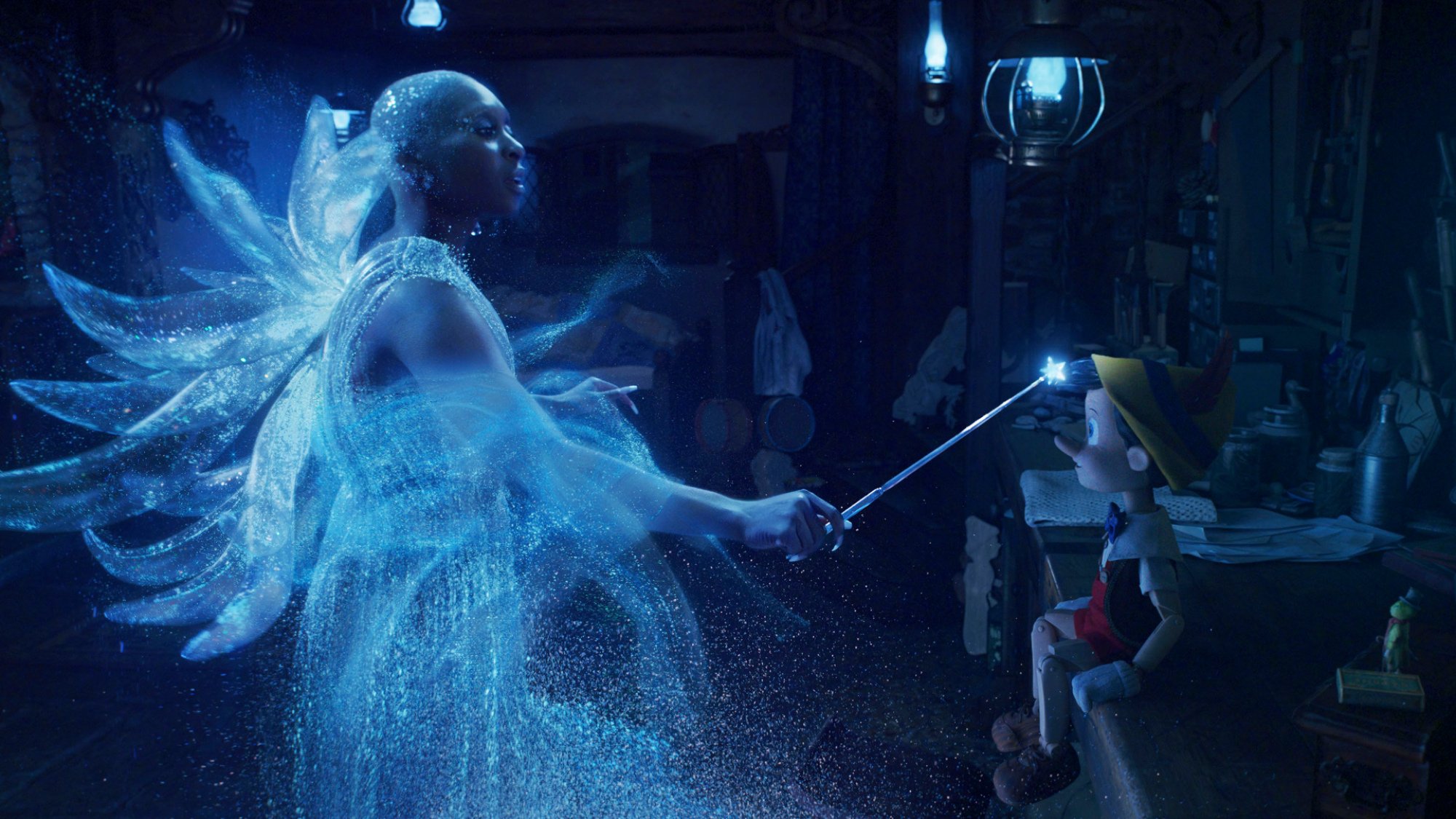 A fairy with glittering wings uses her magic wand on a wooden puppet boy.