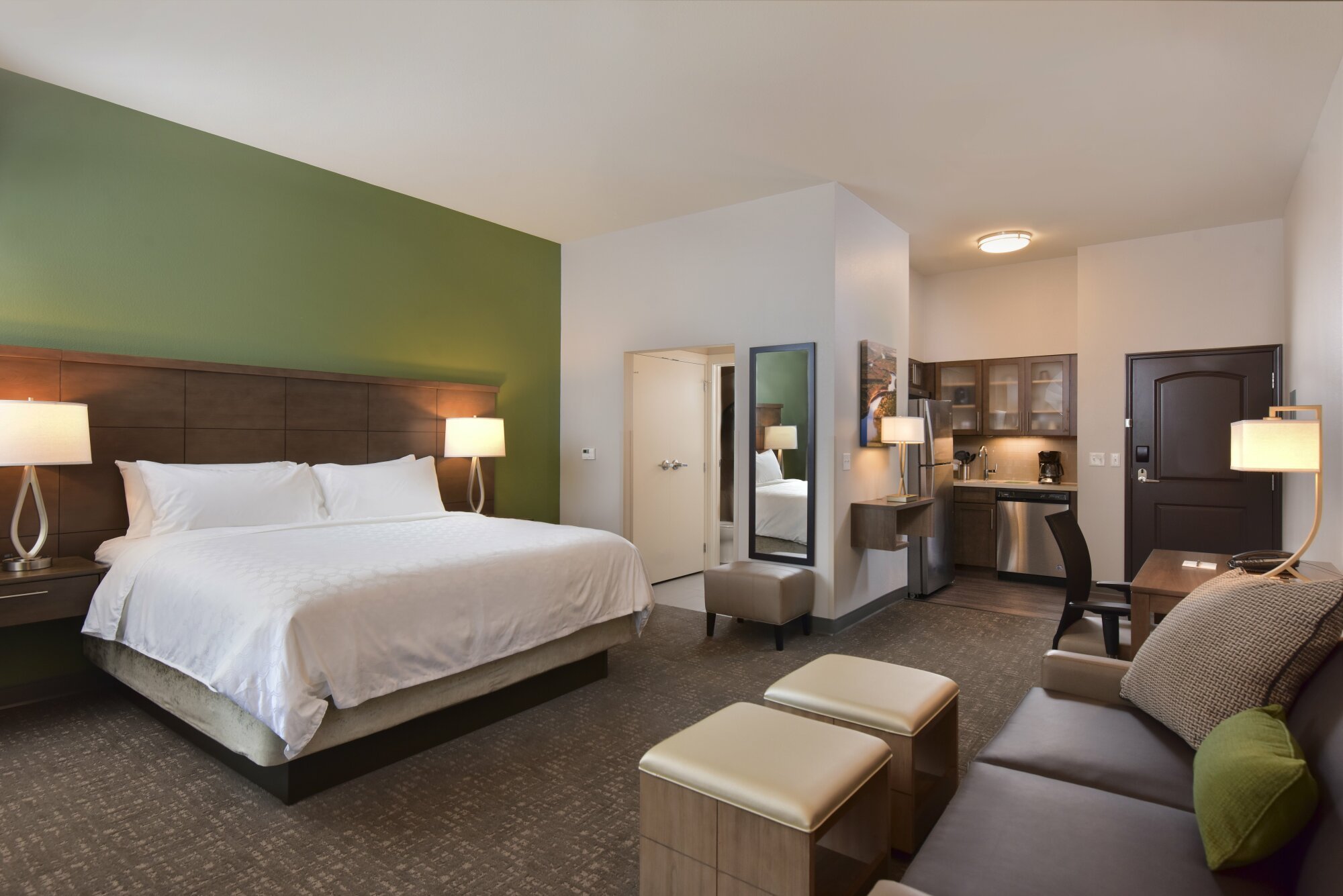 Sleek hotel room with a king sized bed and mini kitchenette