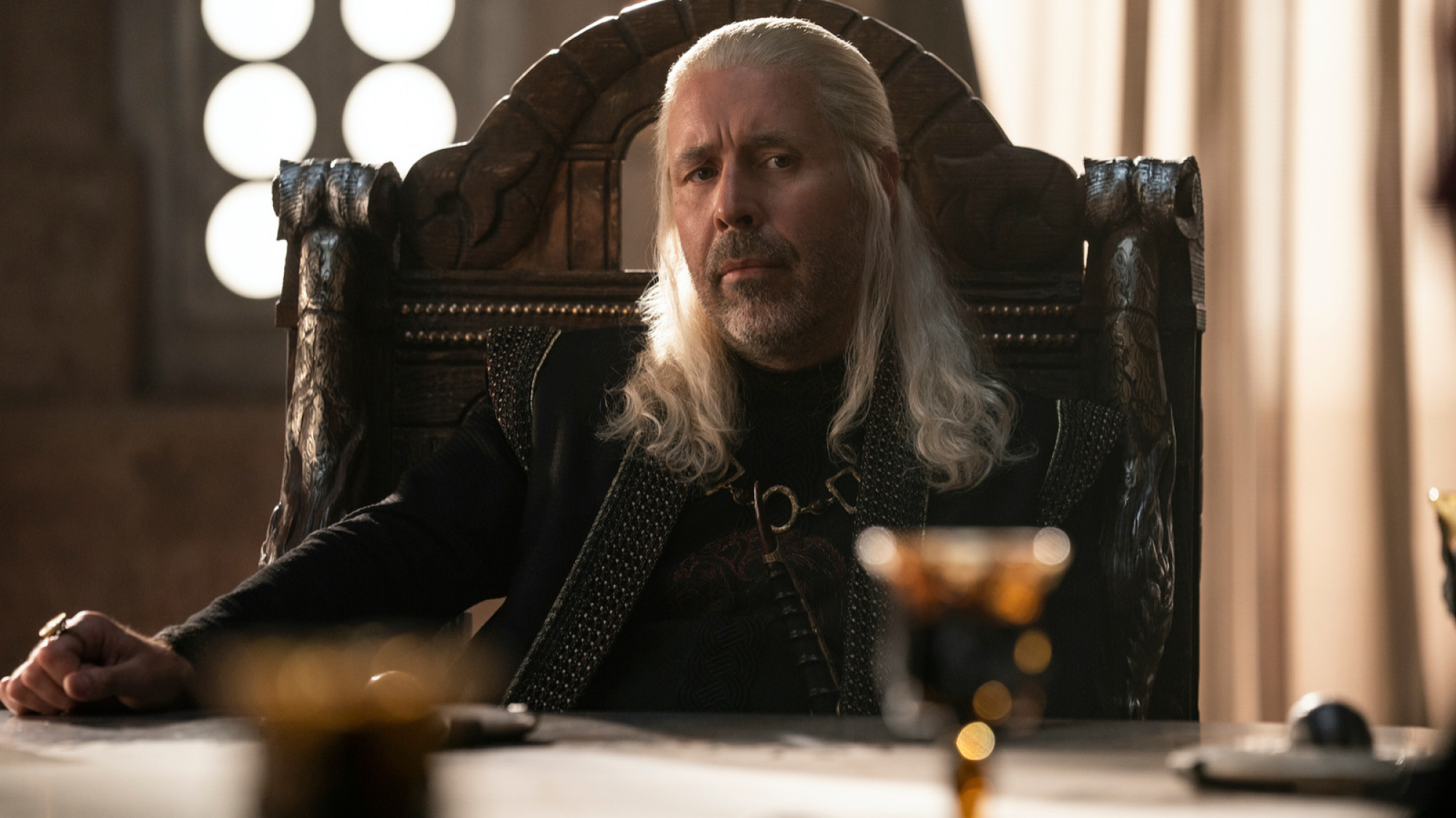 Viserys Targaryen I sits by his table.