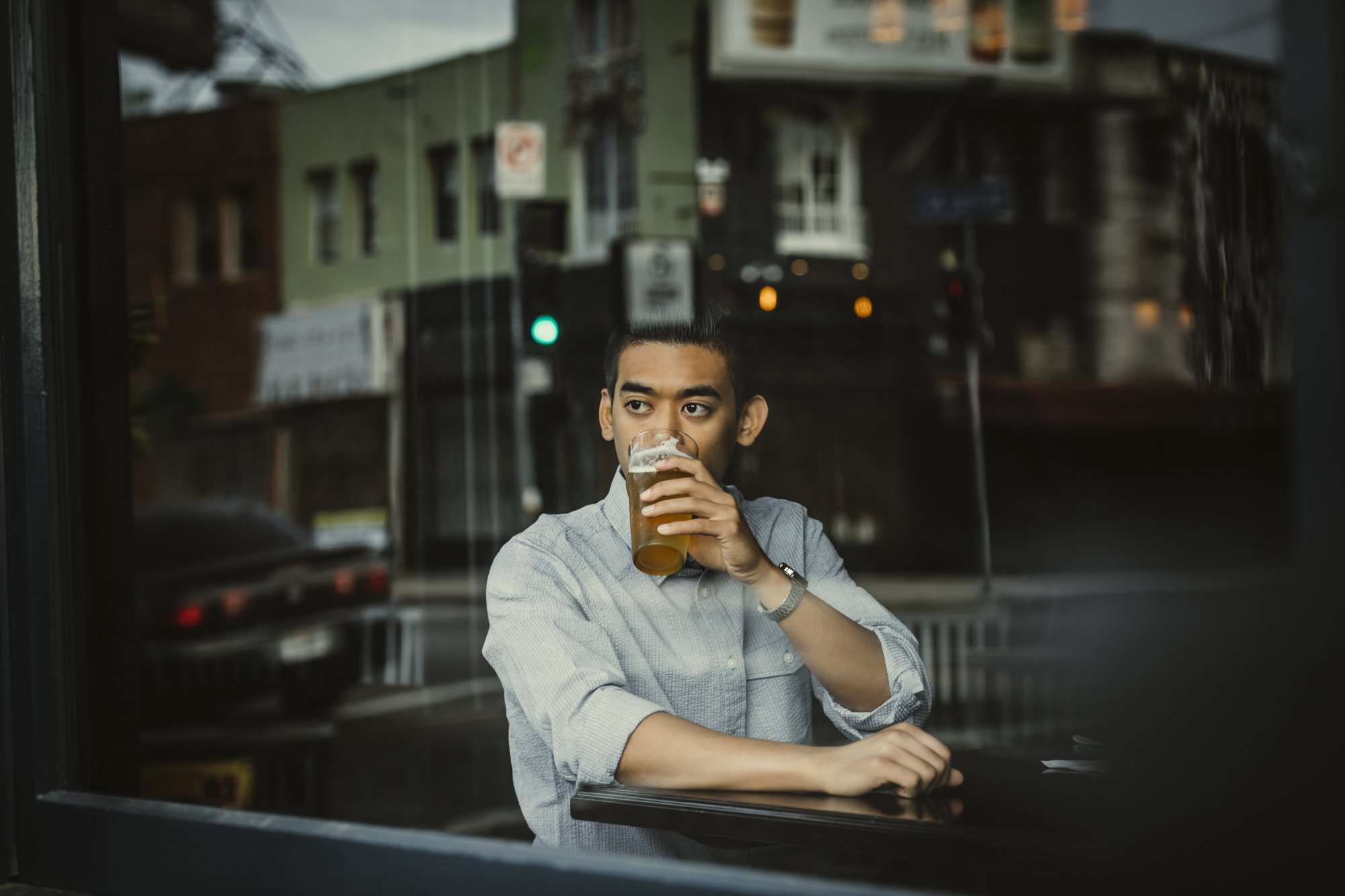 Man relaxing at a restaurant and having a drink while looking out the window