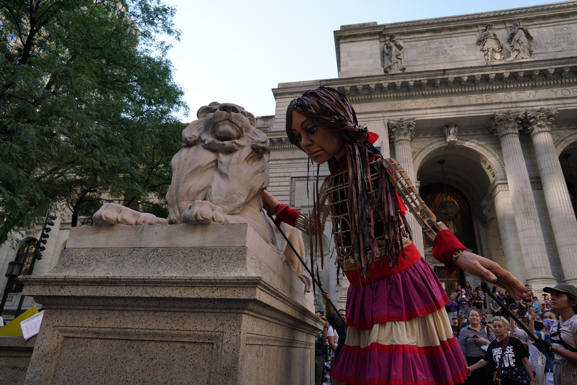 Amal leans over one of the stone lions that rests outside of the New York Public Library.