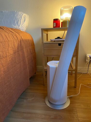 westinghouse fan tilted up in front of a nightstand and next to bed