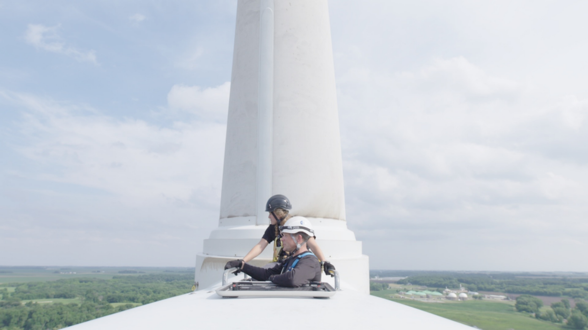 A still from "Paris to Pittsburgh" showing two people at the top of a wind turbine