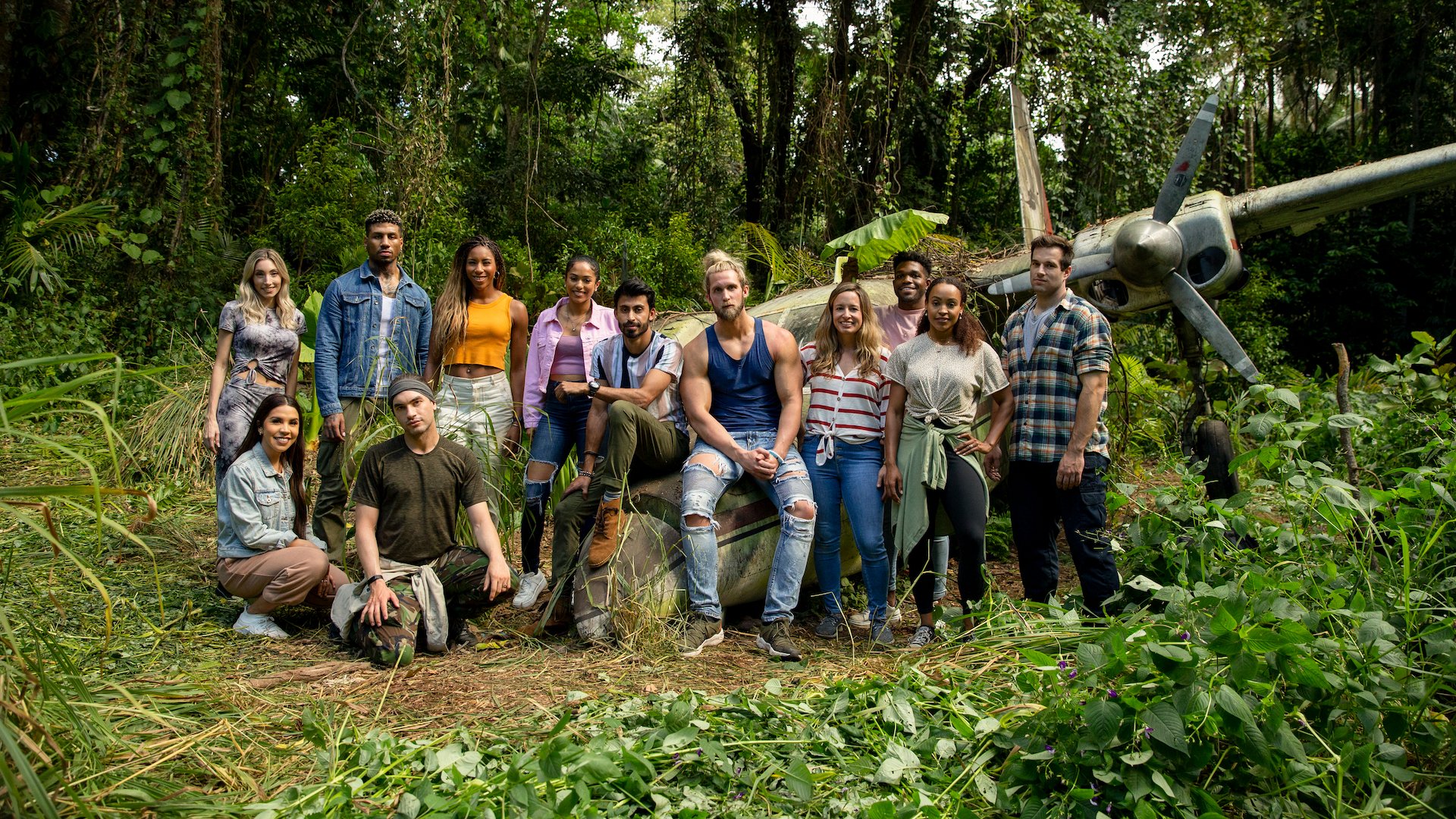 A group of people stand with a plane in the jungle.