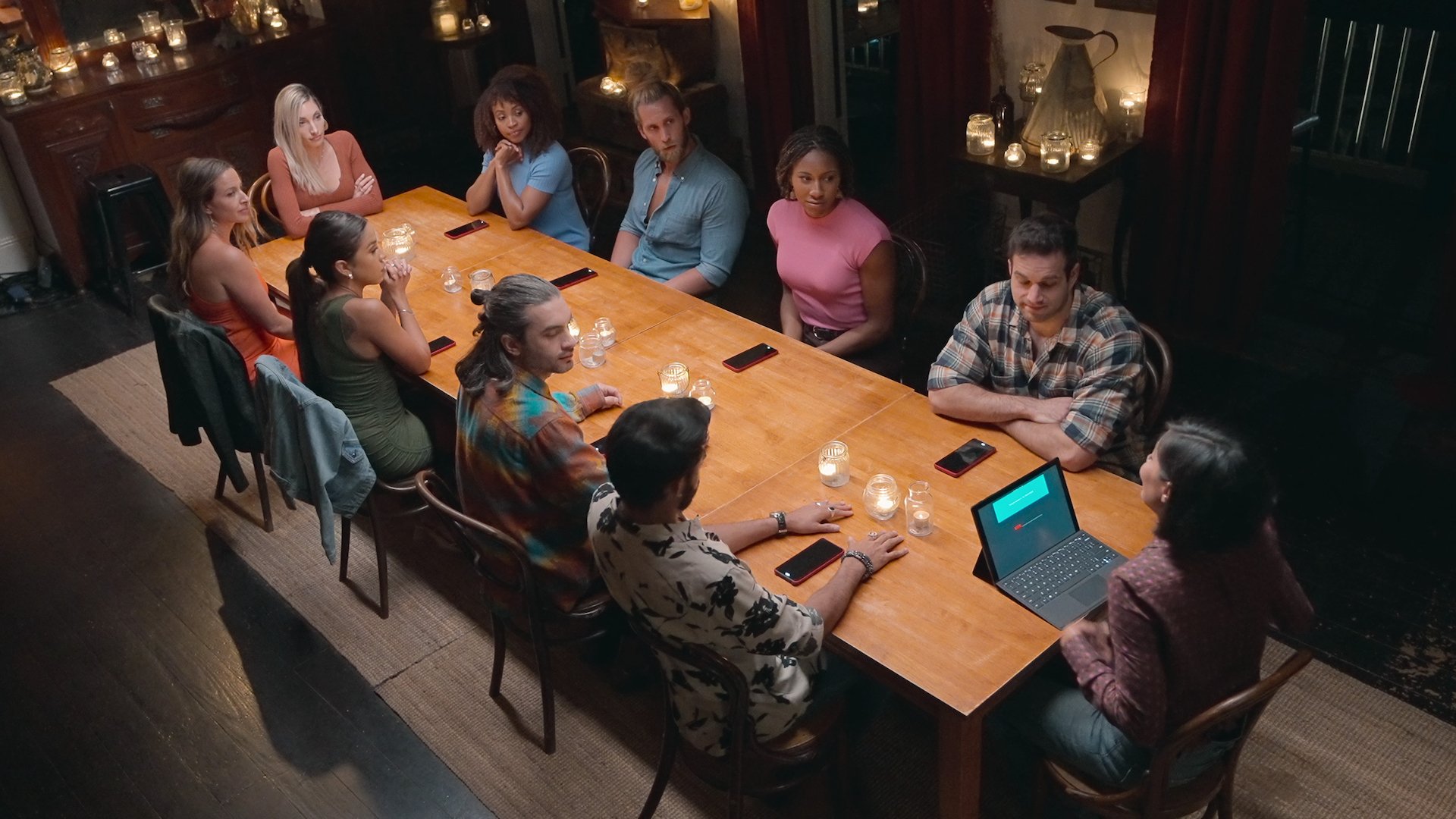 A group of people at a dinner table, and the person at the head has a laptop.