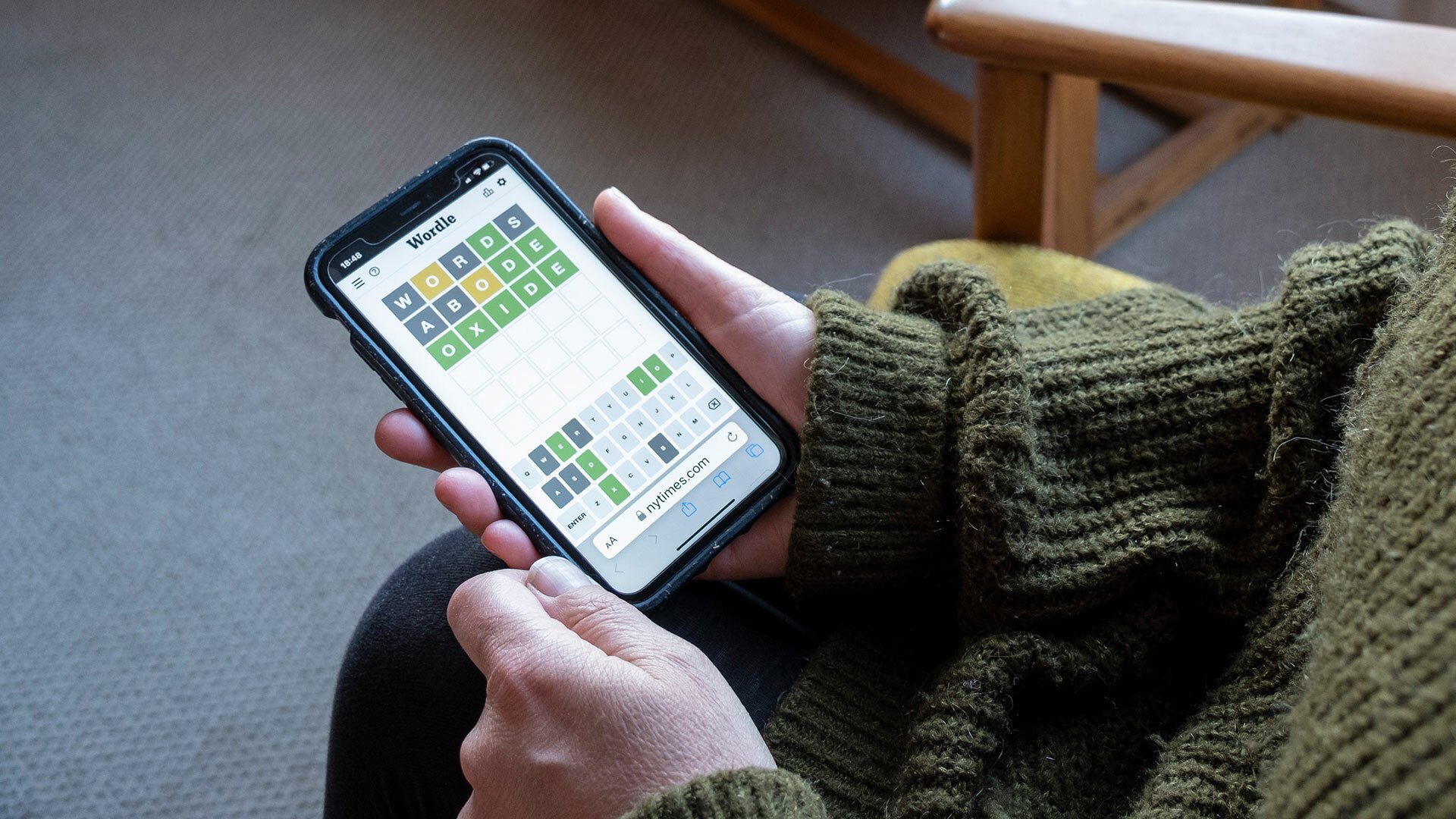 A close-up of a person playing Wordle on a smartphone.