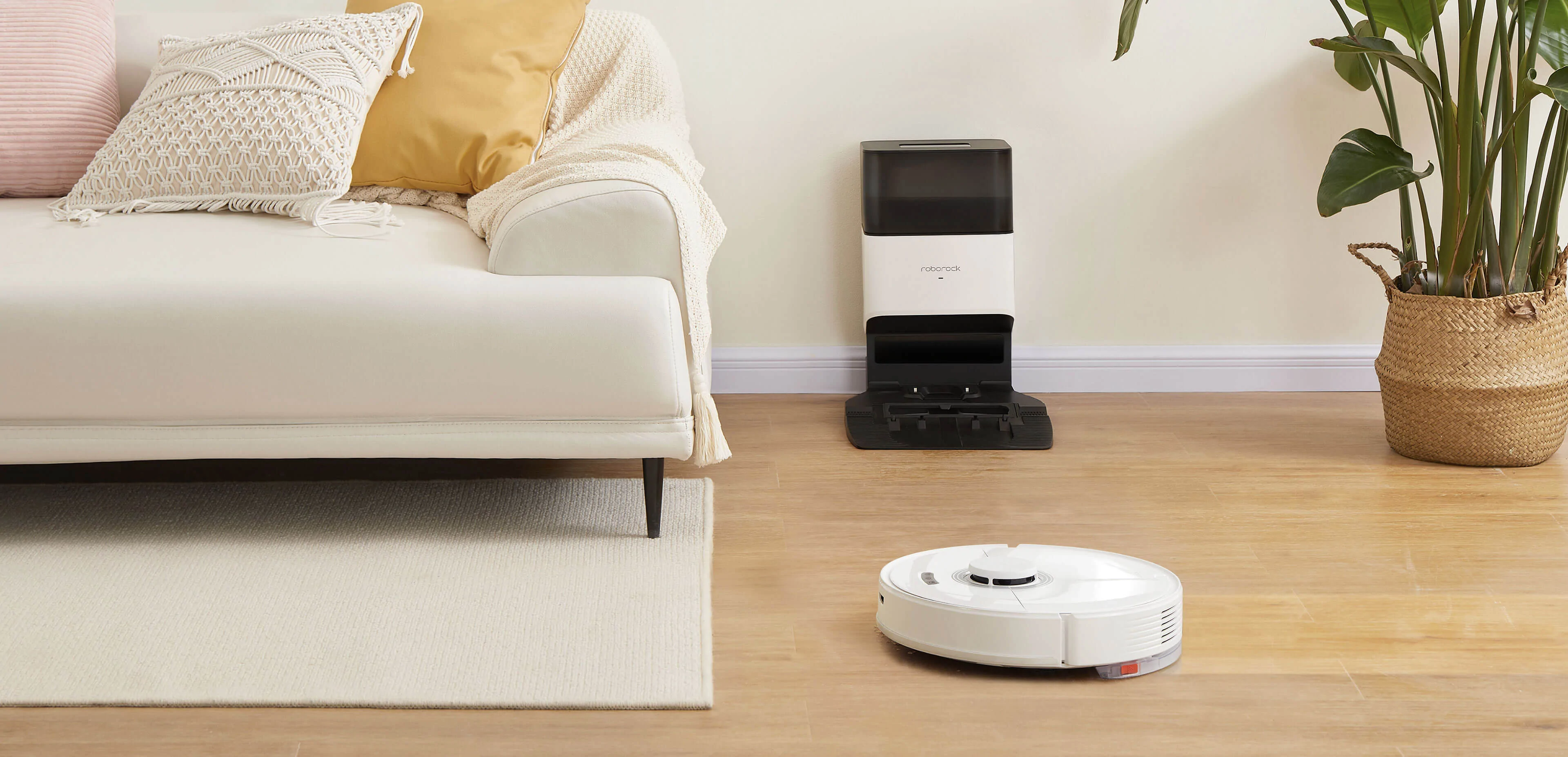 Roborock robot vacuum cleaning hardwood floor with auto-empty dock in background