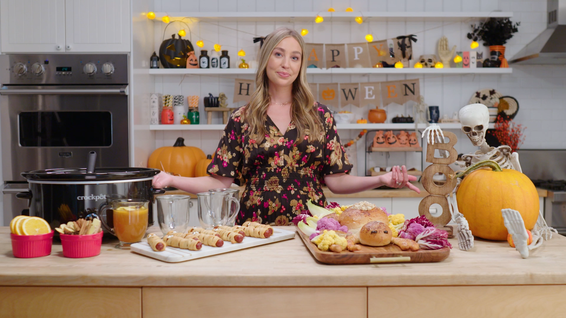 Skyler Bouchard standing in a kitchen, gesturing to a Halloween spread and items from Walmart