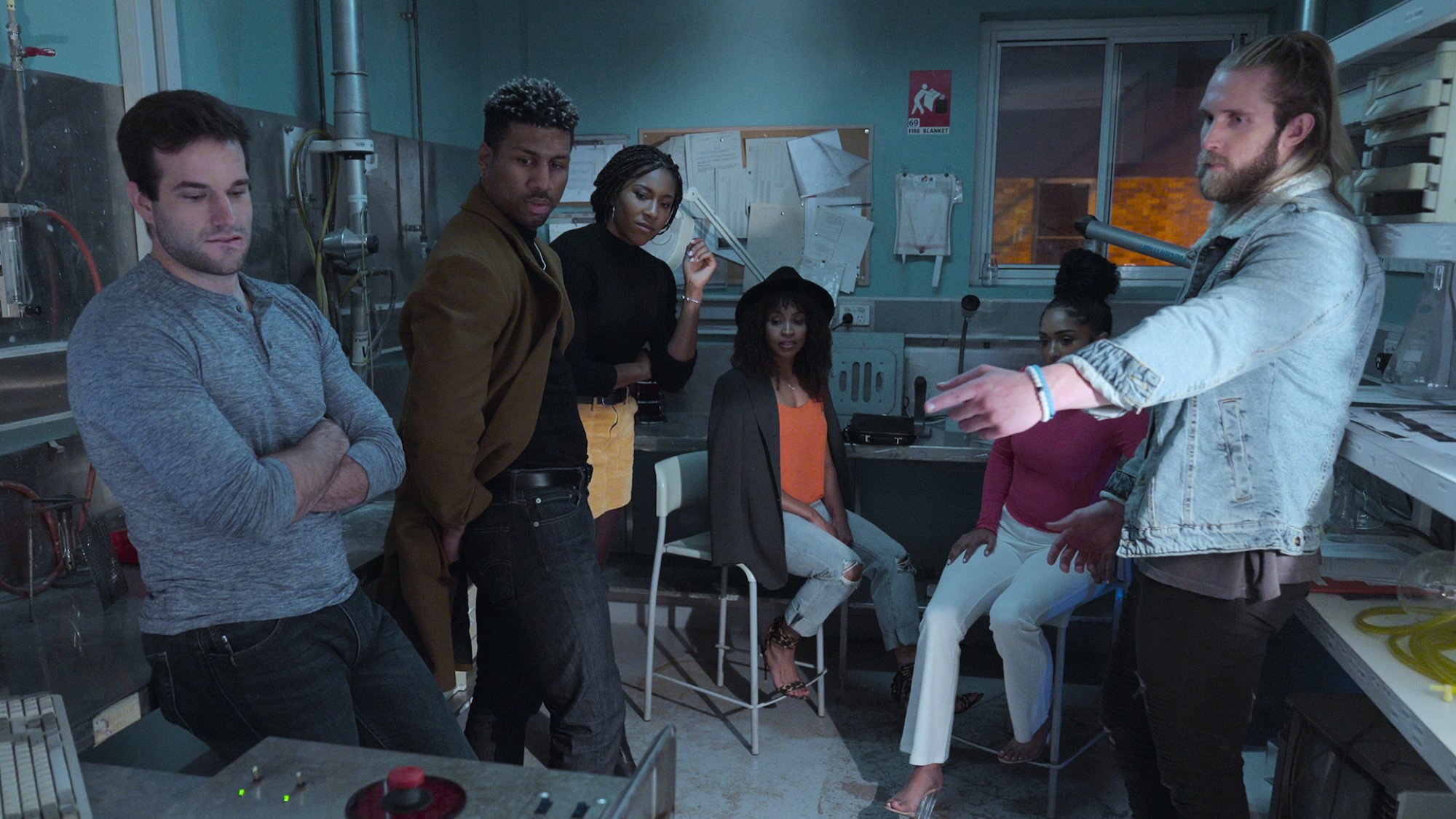 A group of people in an escape room situation stand around.