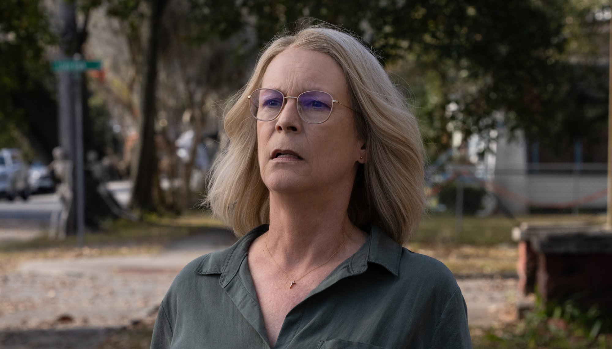 A woman stands in a suburban street looking concerned.