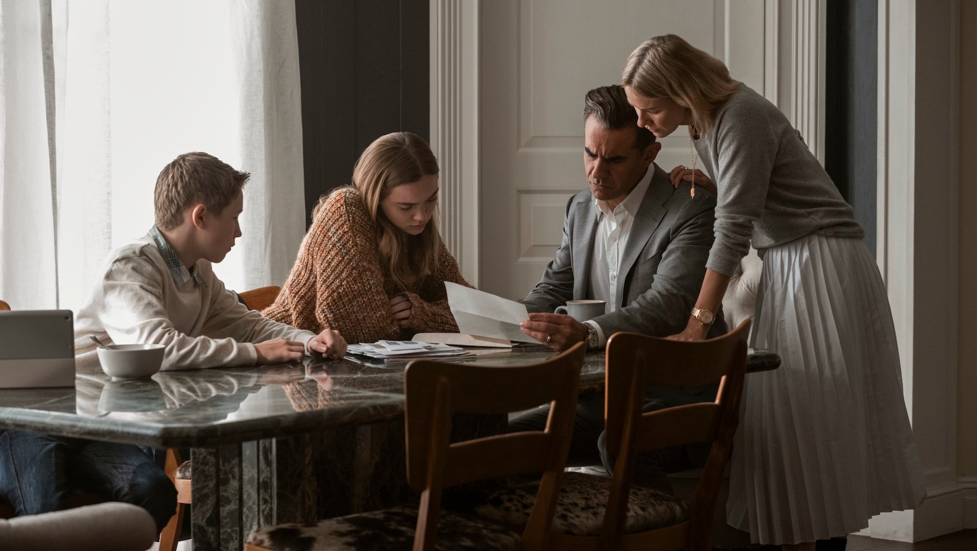 A family sit around a table and read letters.