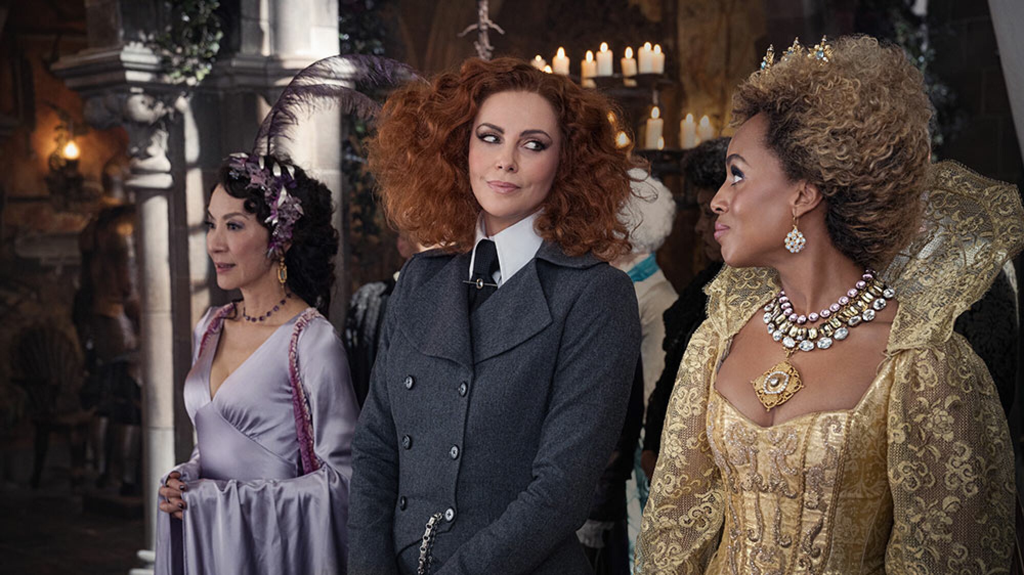 Three women in lavish dress stand in a candle-lit hall.