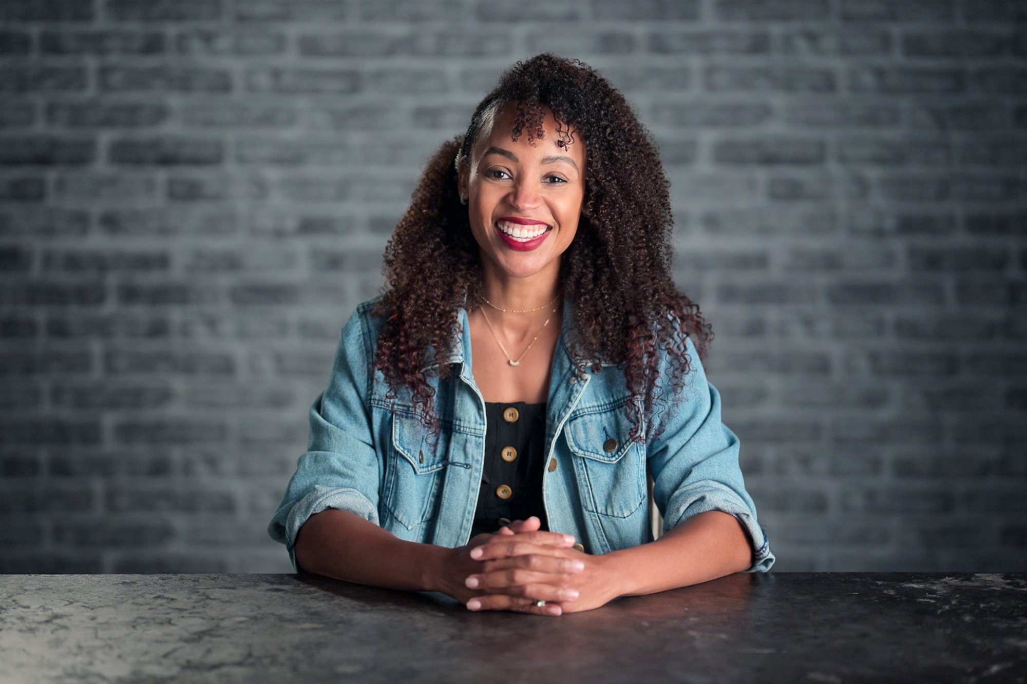 A player on the Netflix series "The Mole" sits facing the camera, a woman with a denim shirt.