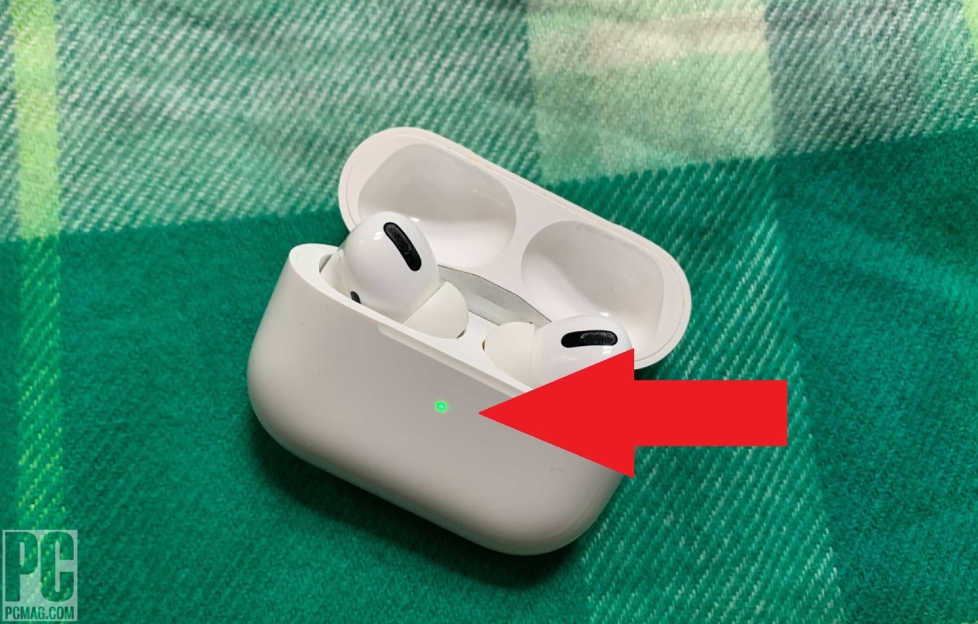 AirPods case open showing a green indicator light