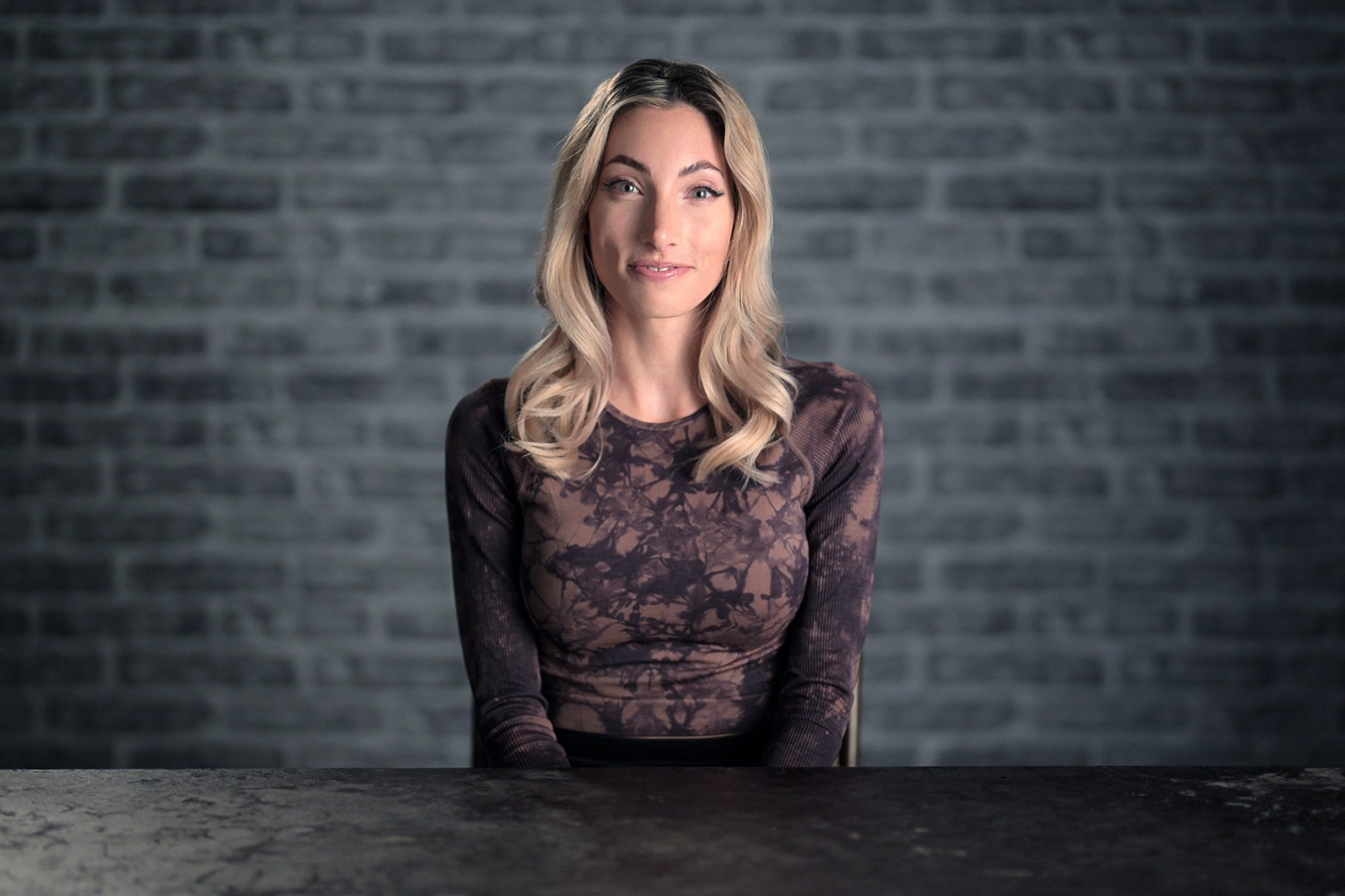A player on the Netflix series "The Mole" sits facing the camera, a woman with a purple top.