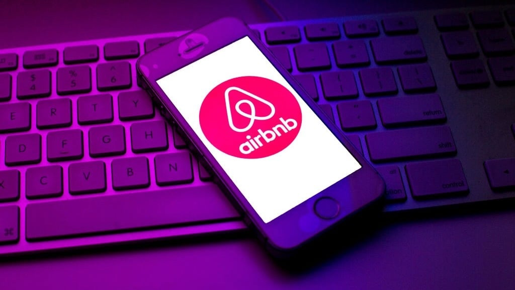 phone with airbnb logo on top of keyboard lit in neon