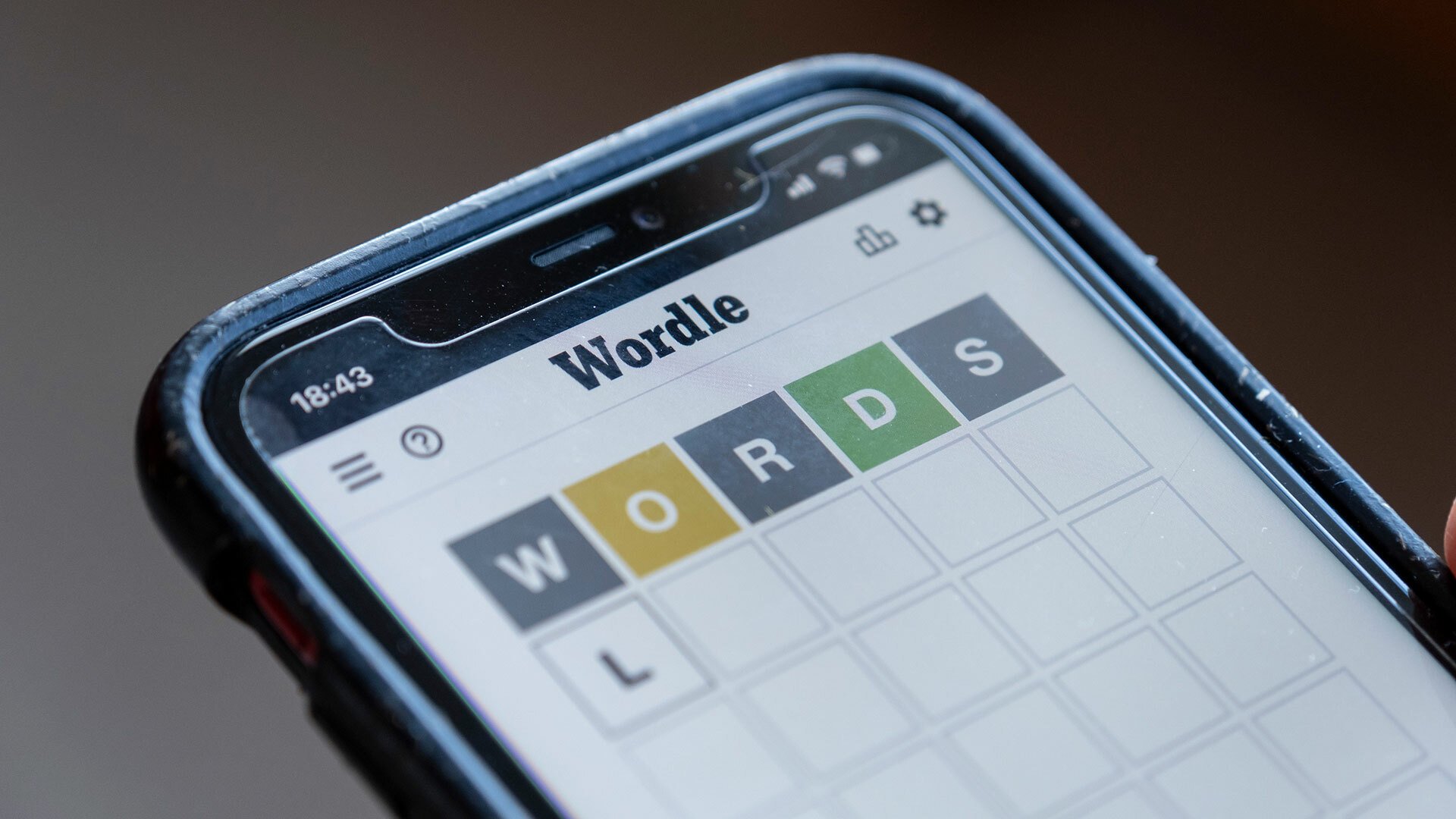 A close-up of a person playing Wordle on a smartphone.