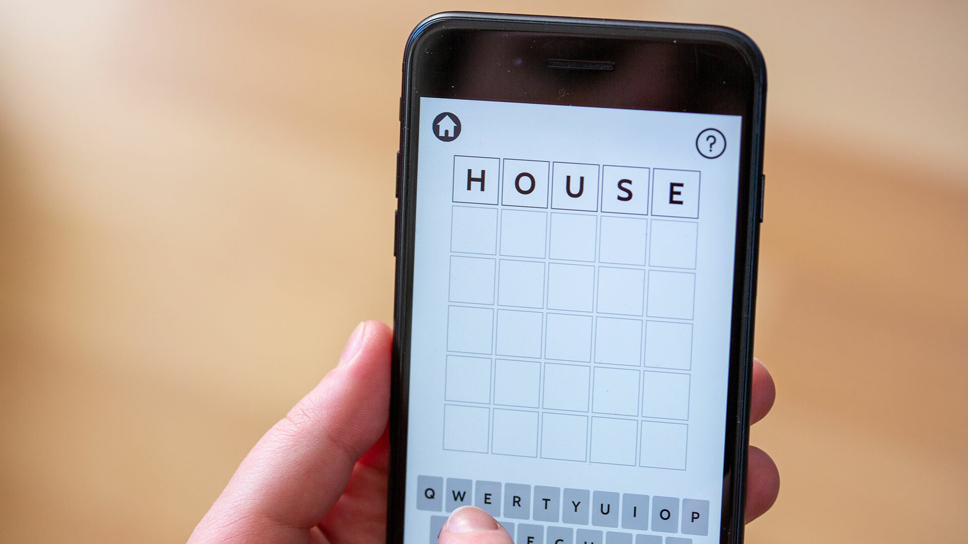 A close-up of a person playing Wordle on a smartphone.