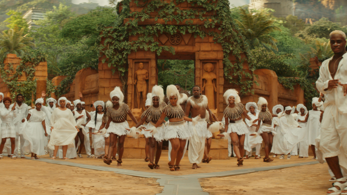 A group of African dancers dressed in traditional tribal clothing gather together for performance. 