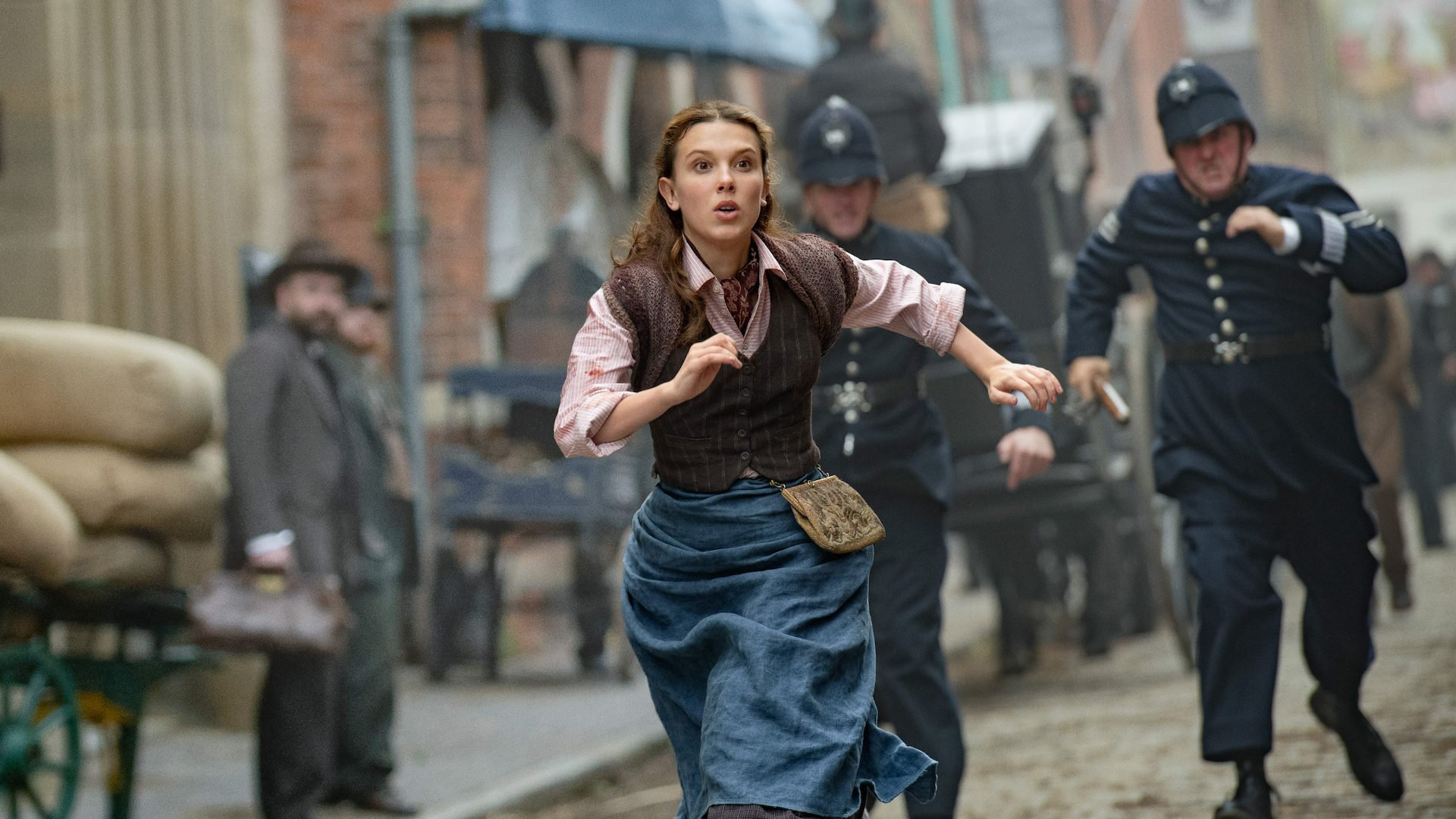 On a film set resembling a Victorian street in London, a young woman runs from the police.