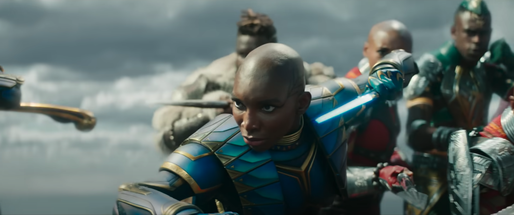 Michaela Coel as Aneka in the Midnight Angels suit, a Black woman with a shaved head wearing bright blue armor.