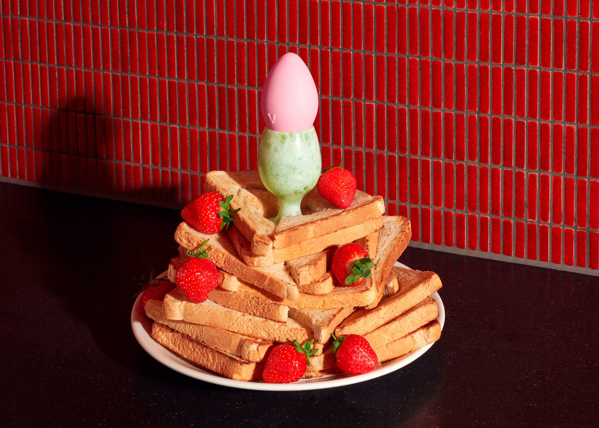 A small vibrator pictures on top of a plate of toast and strawberries.