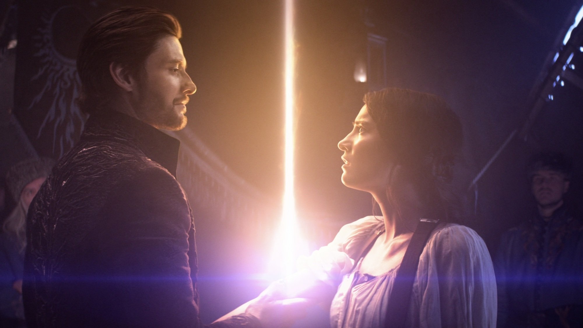 A man in a dark cloak holds his hand over a young woman's arm. A ray of light shines from where he's holding her arm.