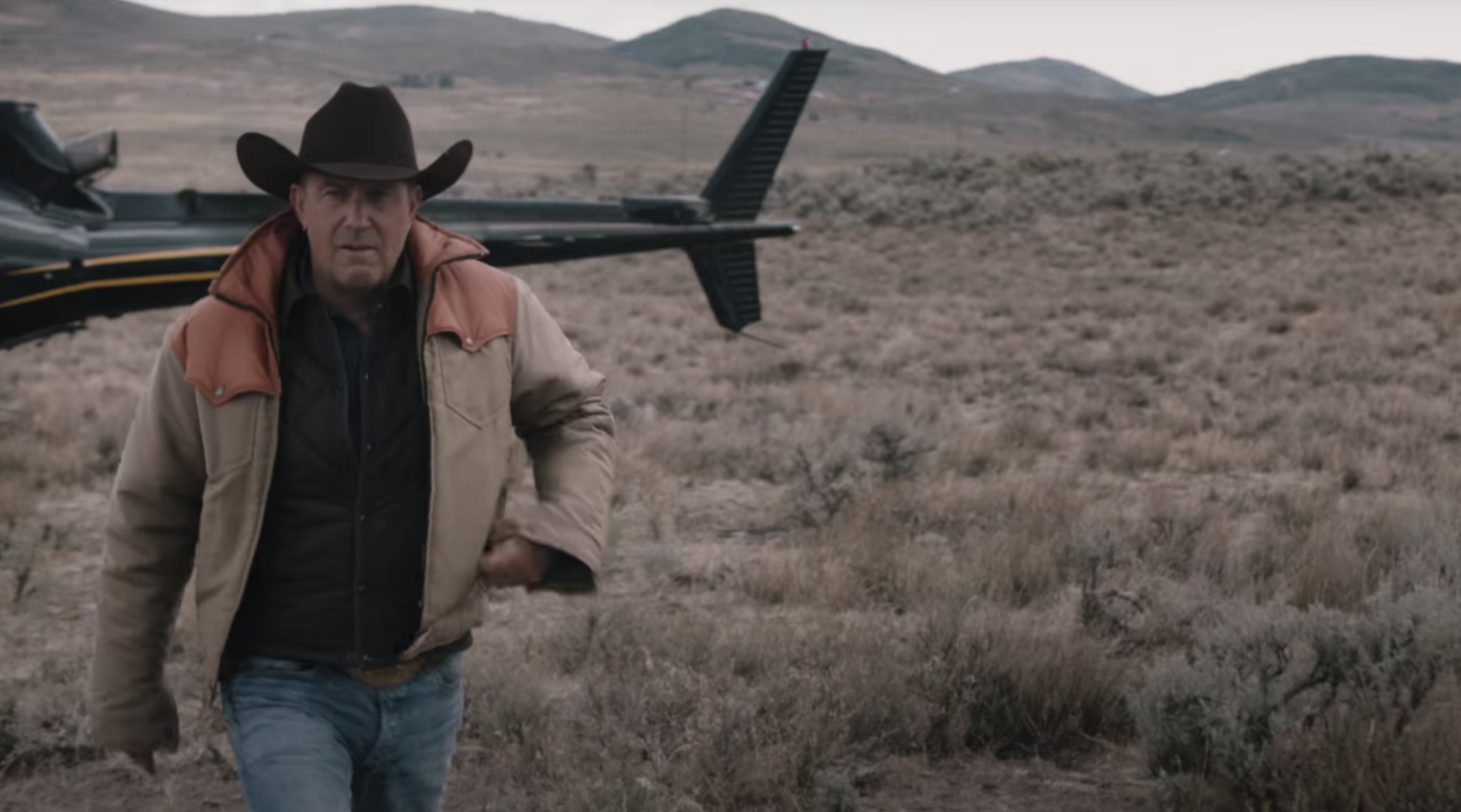 A man in a cowboy hat walks away from a helicopter.