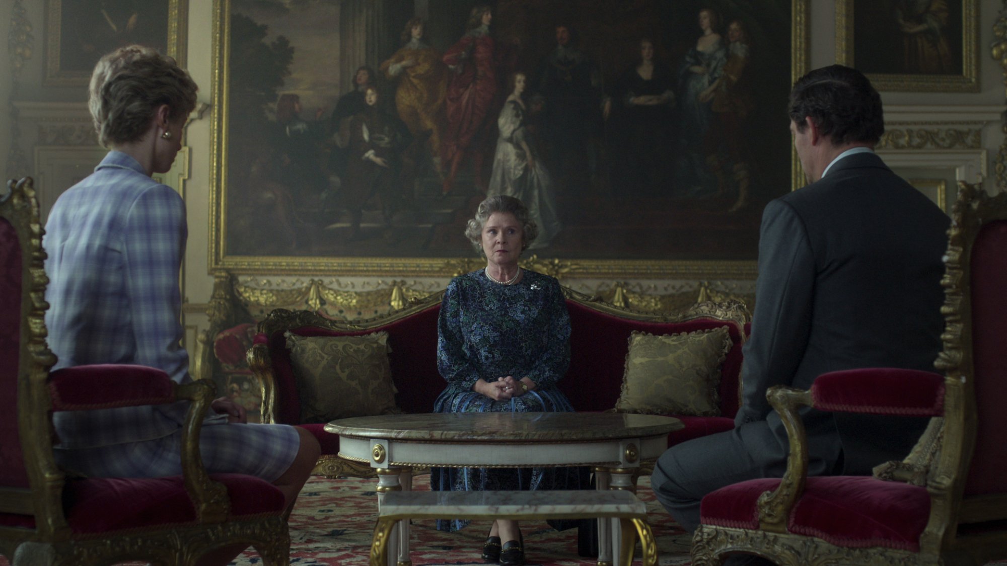 An actor resembling Queen Elizabeth II sits between actors resembling Charles and Diana.