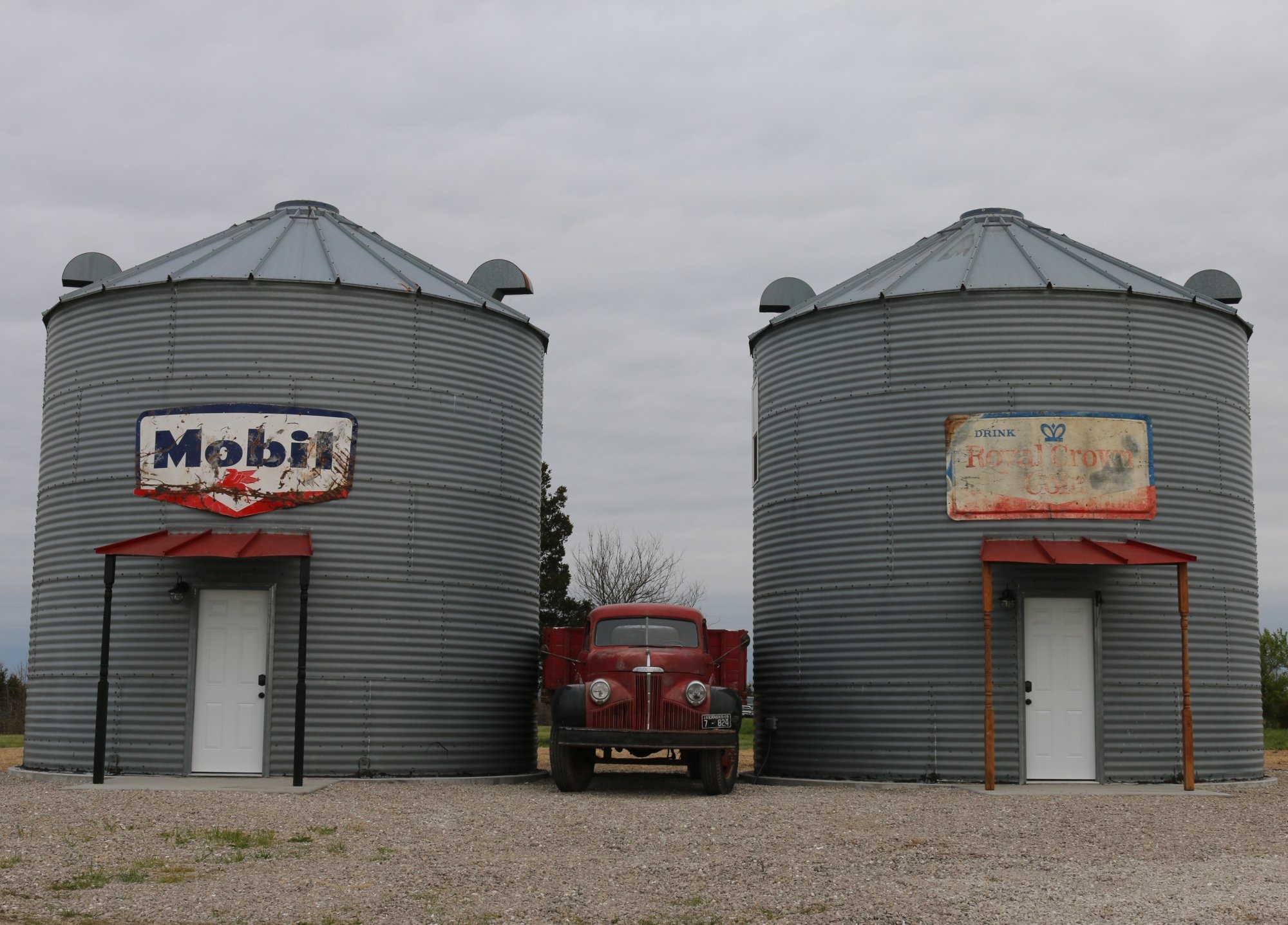 Airbnb listing of two gray grain bins with an antique truck in the middle