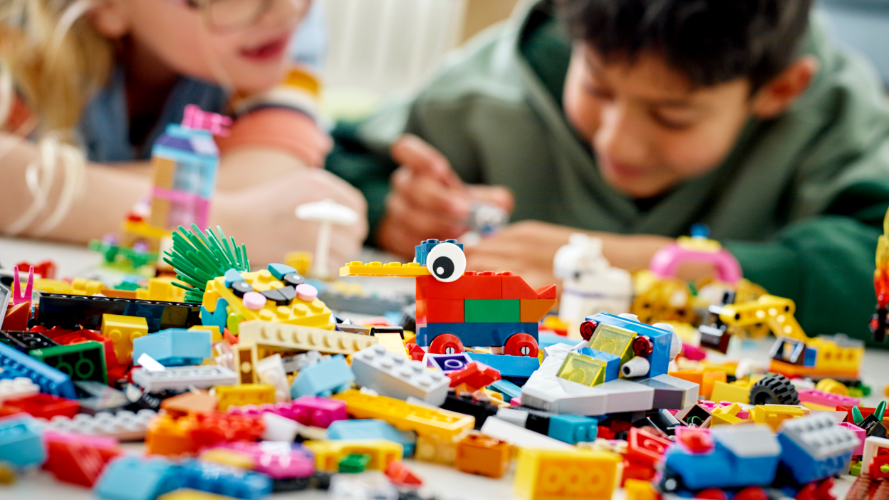 Two children are building a set using colorful LEGO bricks.
