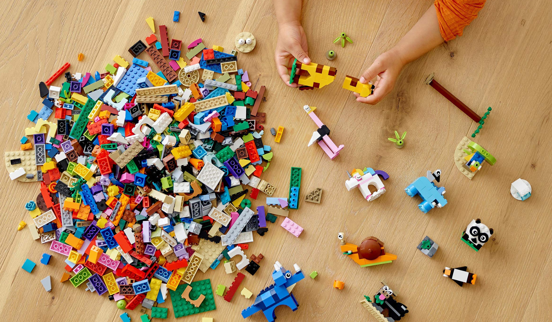 Aerial view of child playing with LEGOs on hardwood floor