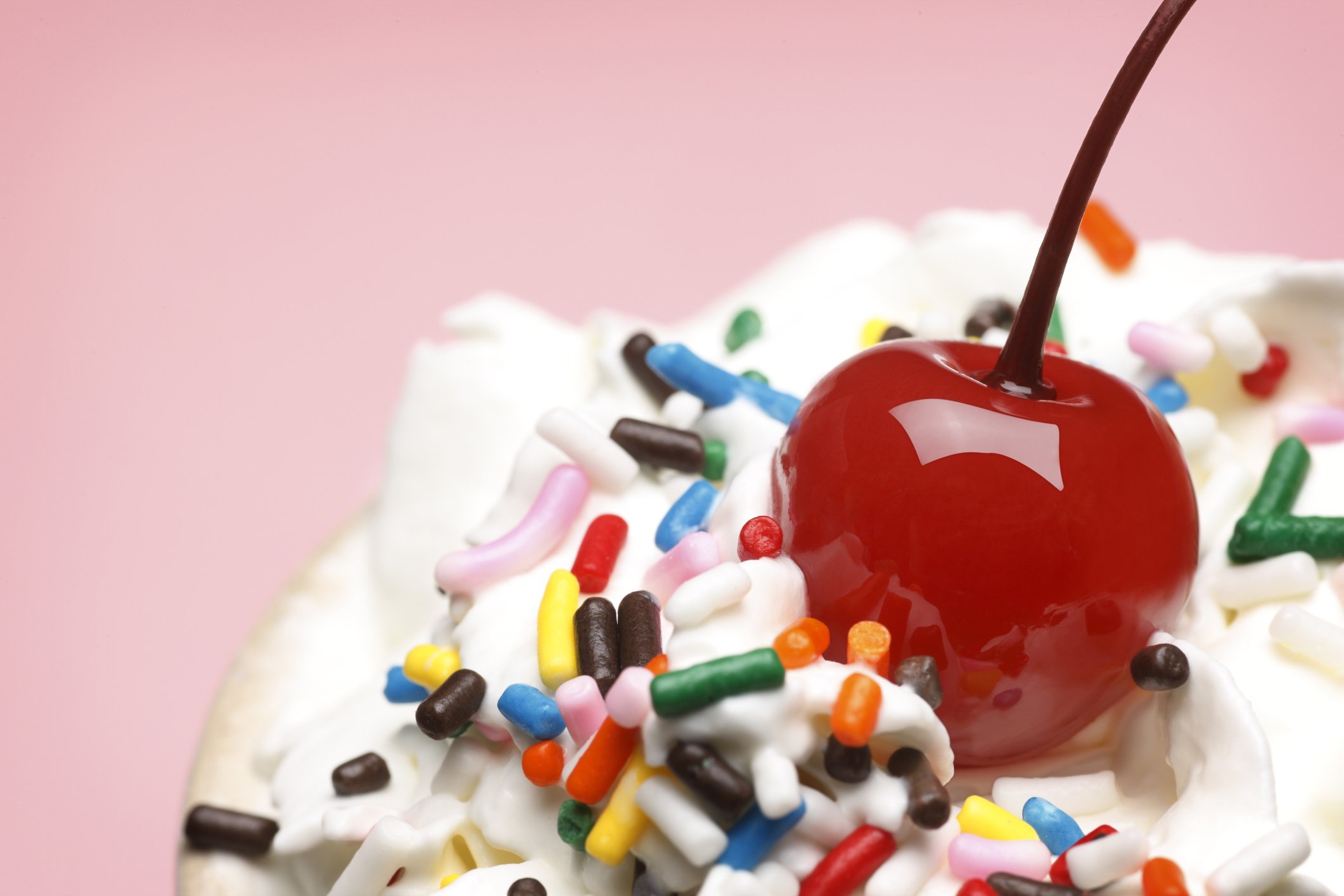 Whipped cream with sprinkles and a glacé cherry on top