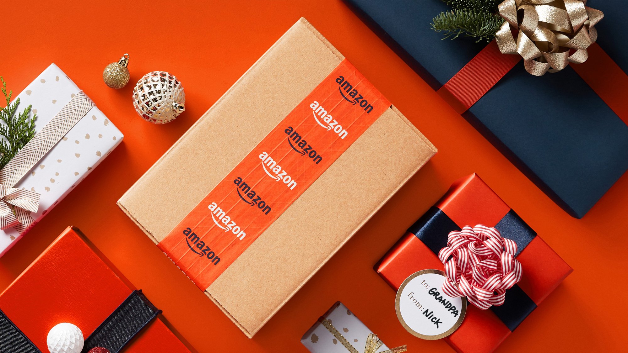 Amazon box and wrapped gifts sitting on orange surface