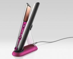 the black nickel/fuchsia dyson corrale hair straightener on its charging dock