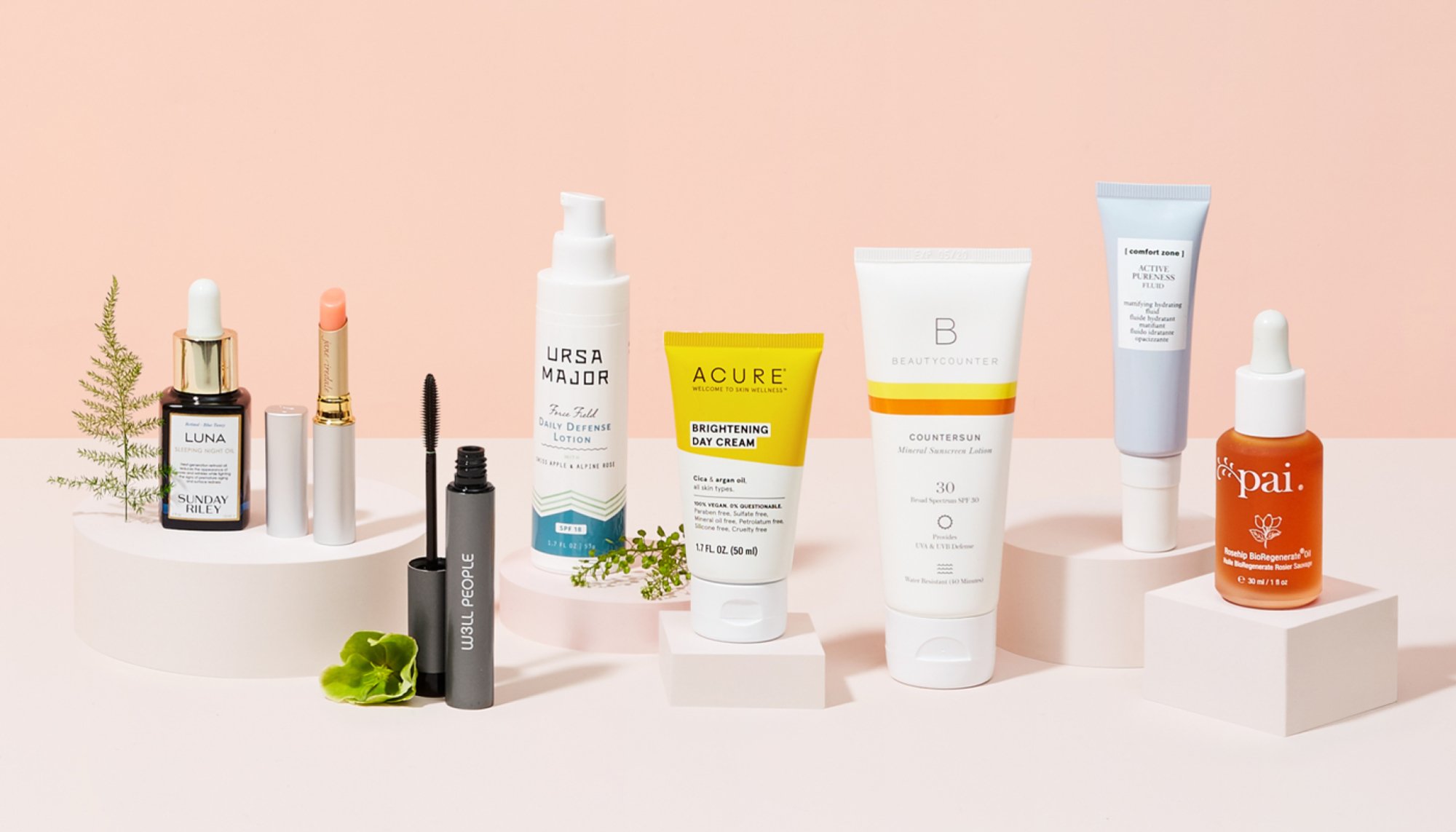 a collection of beauty products against a pale pink background