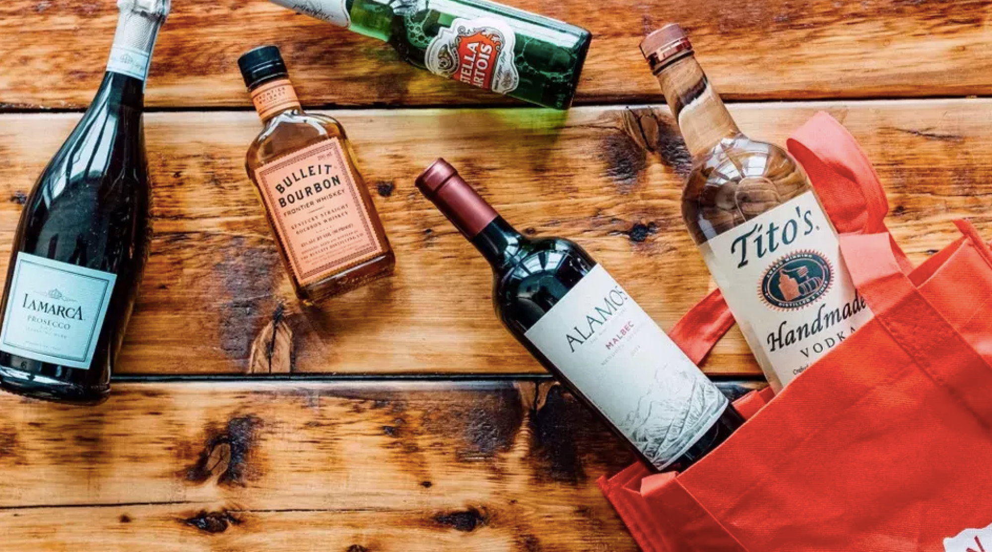 a collection of liquor and wine bottles laying on a wooden table