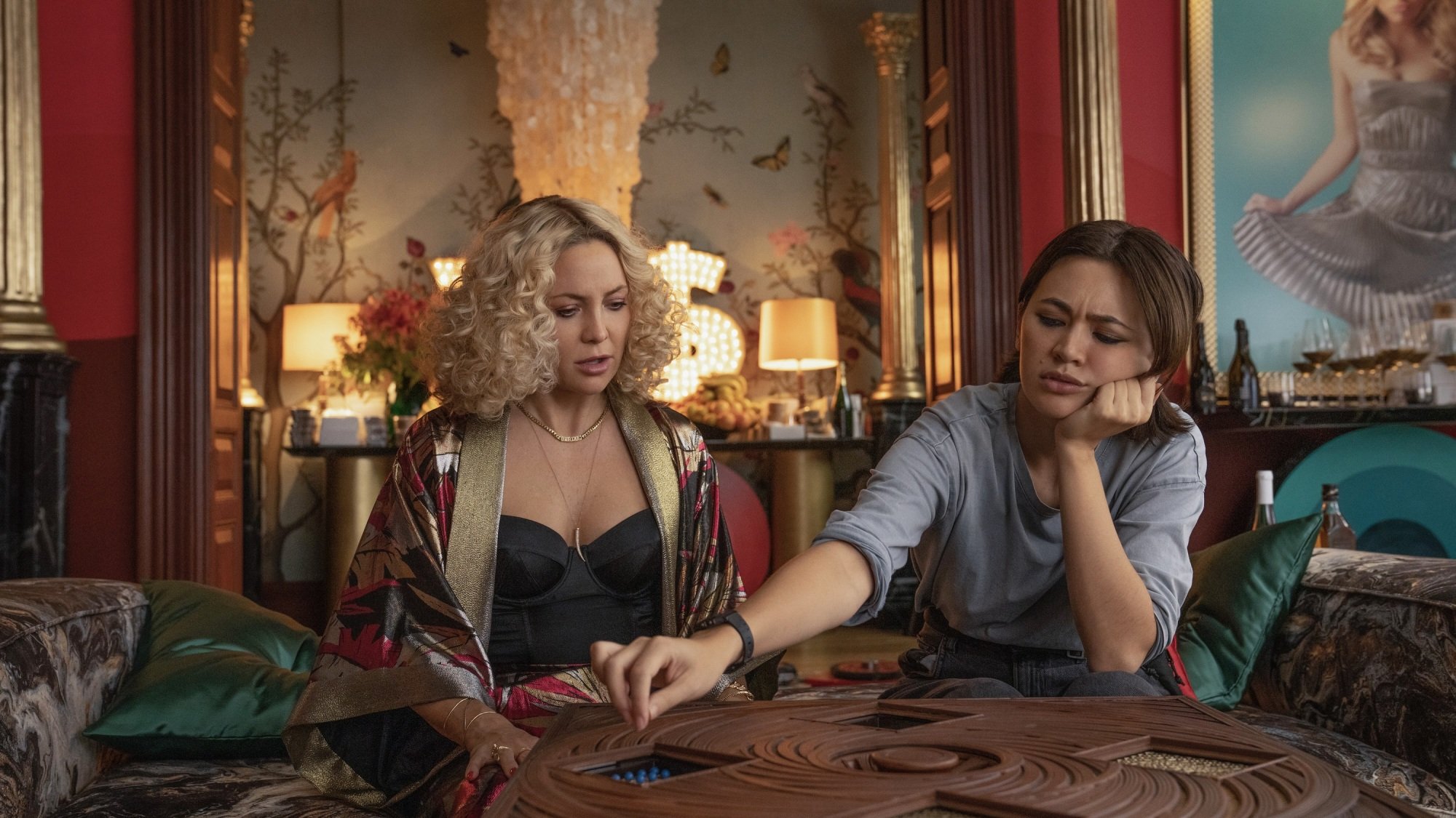 Two women work on a puzzle in a lavishly decorated living room.