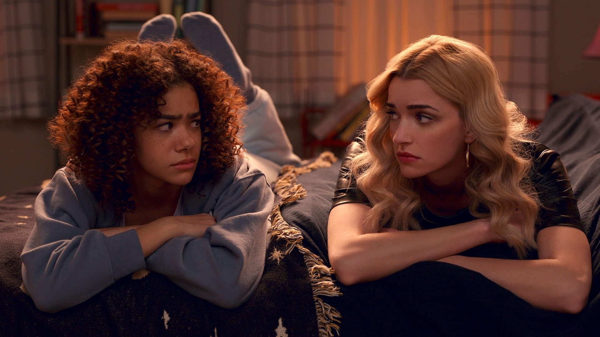 A teen girl and young woman sit beside each other looking worriedly at each other.