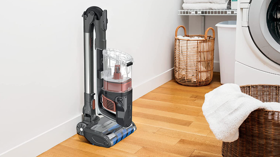 Shark vacuum to the left inside a laundry room. Two baskets and towel racks are present